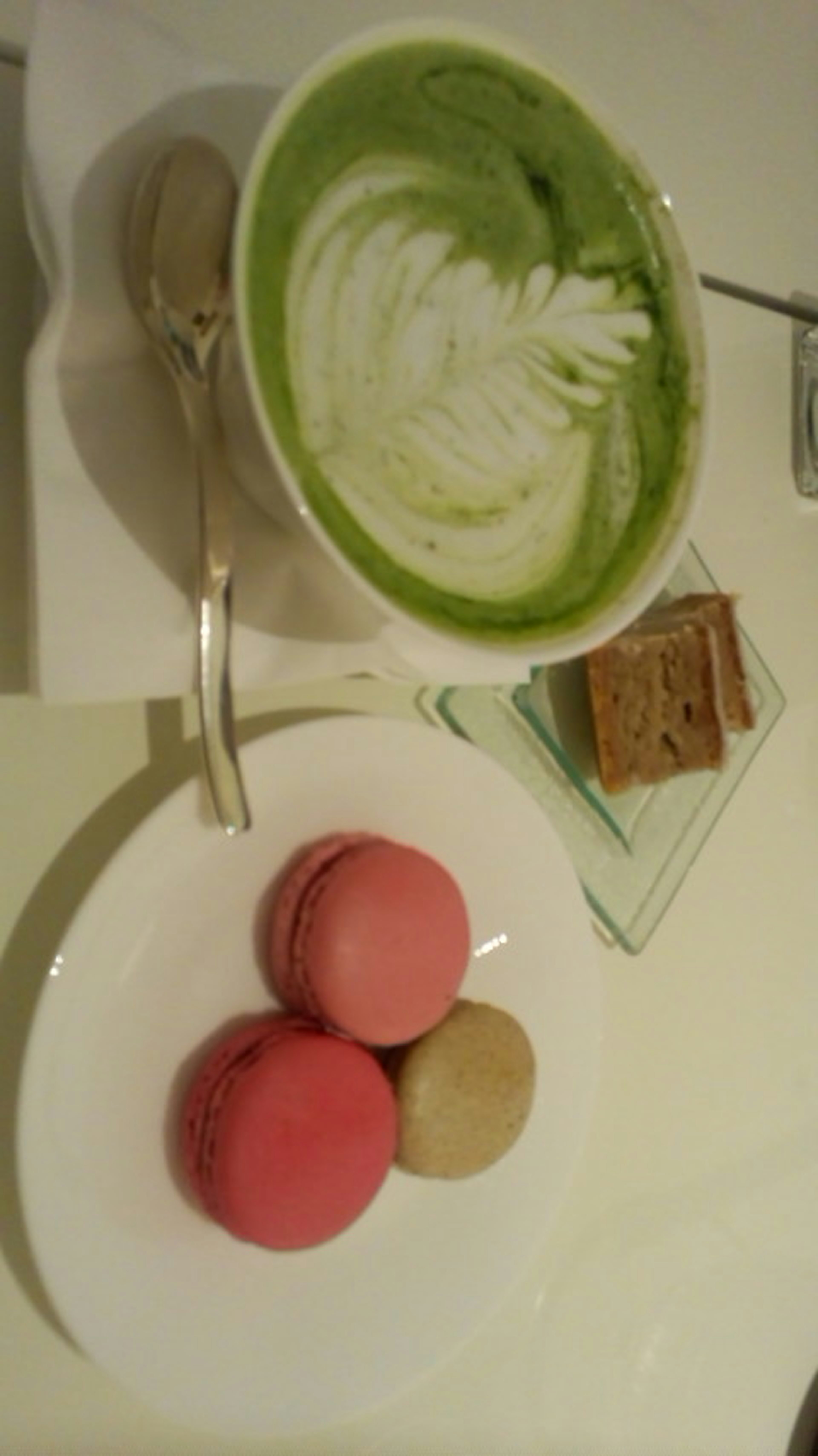 Mesa de café con latte de matcha y un plato de macarons