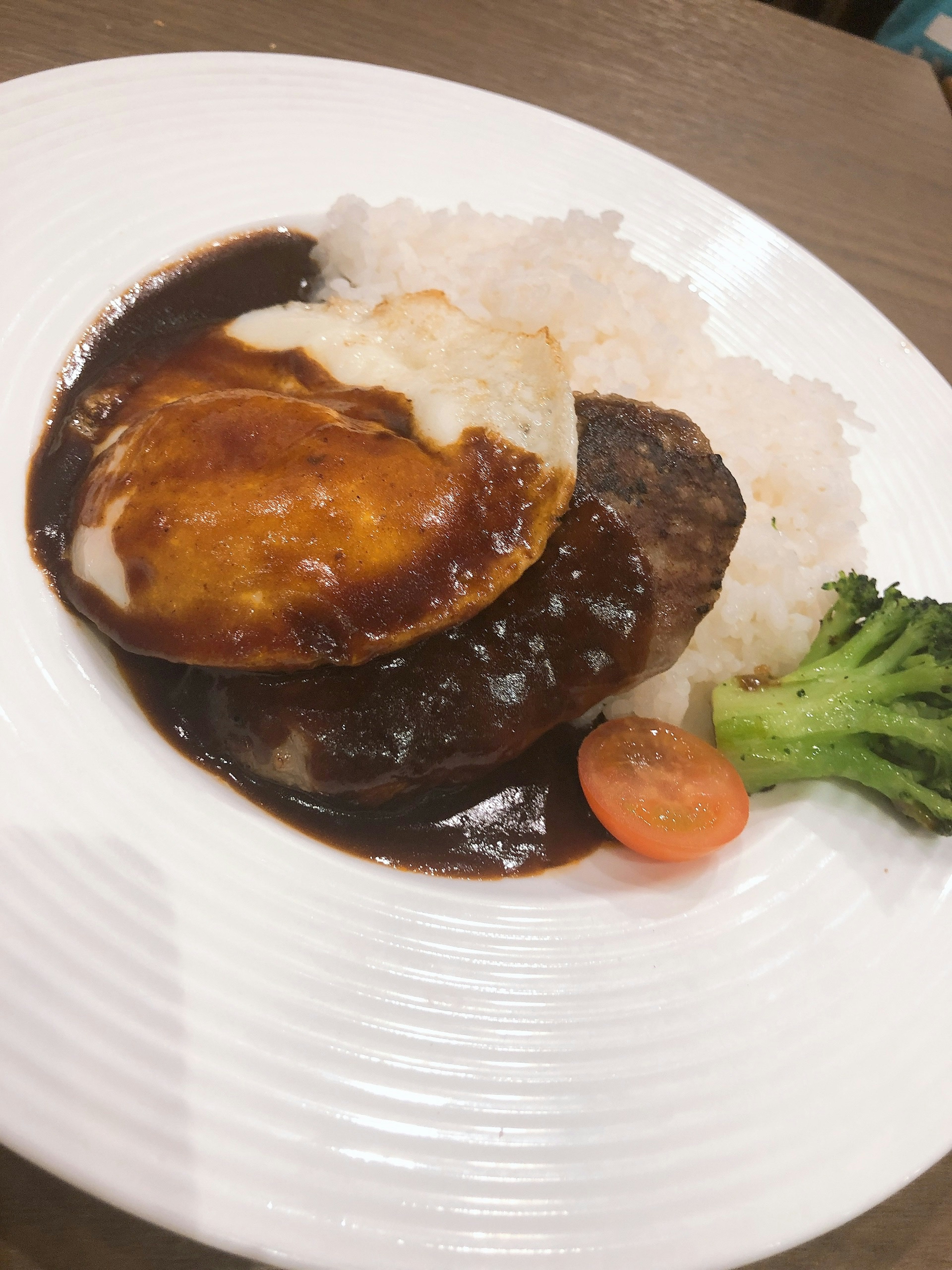 Hidangan disajikan di piring putih dengan nasi dan steak hamburger dengan saus