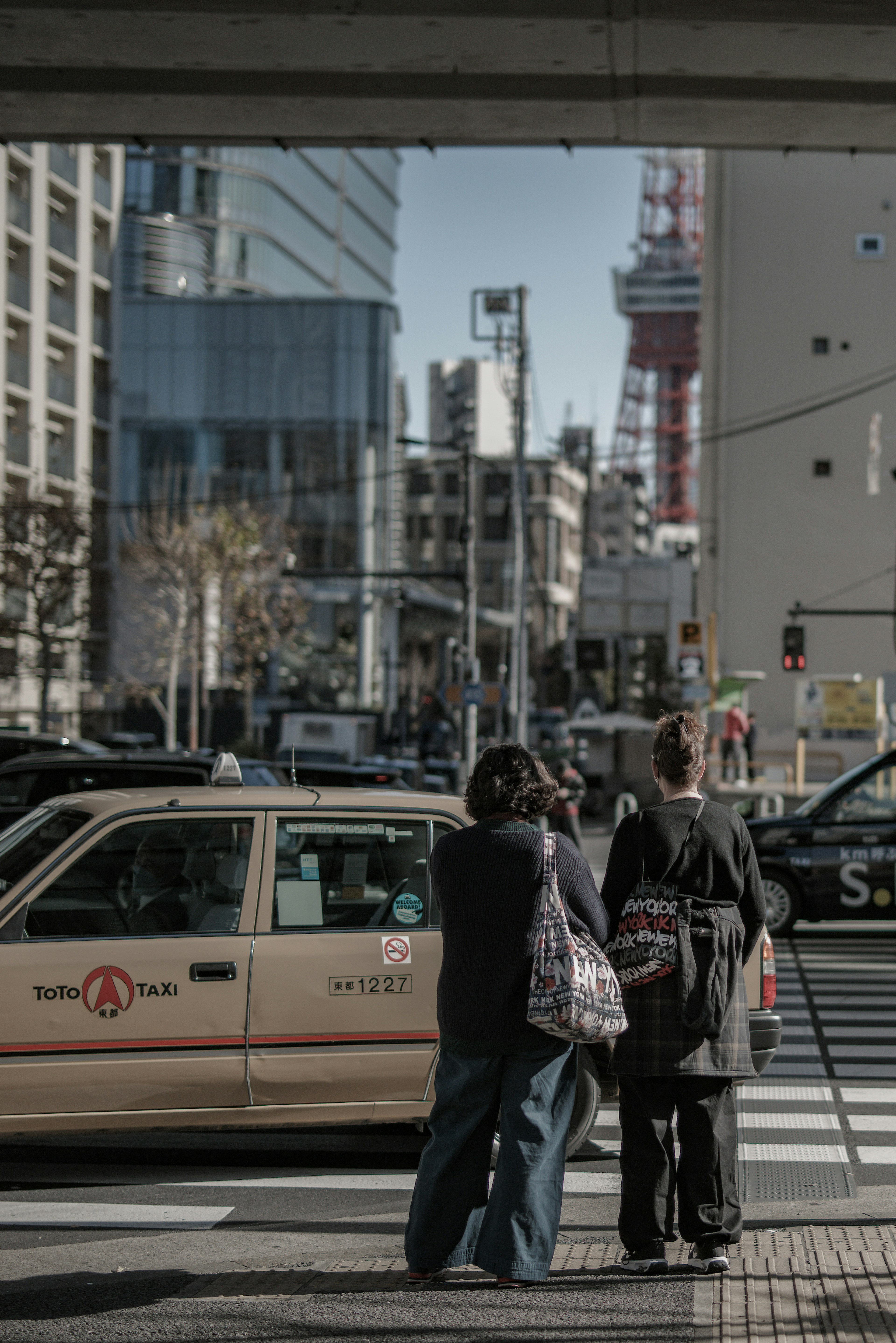 Des personnes attendant un taxi à une intersection de Tokyo avec la Tour de Tokyo en arrière-plan