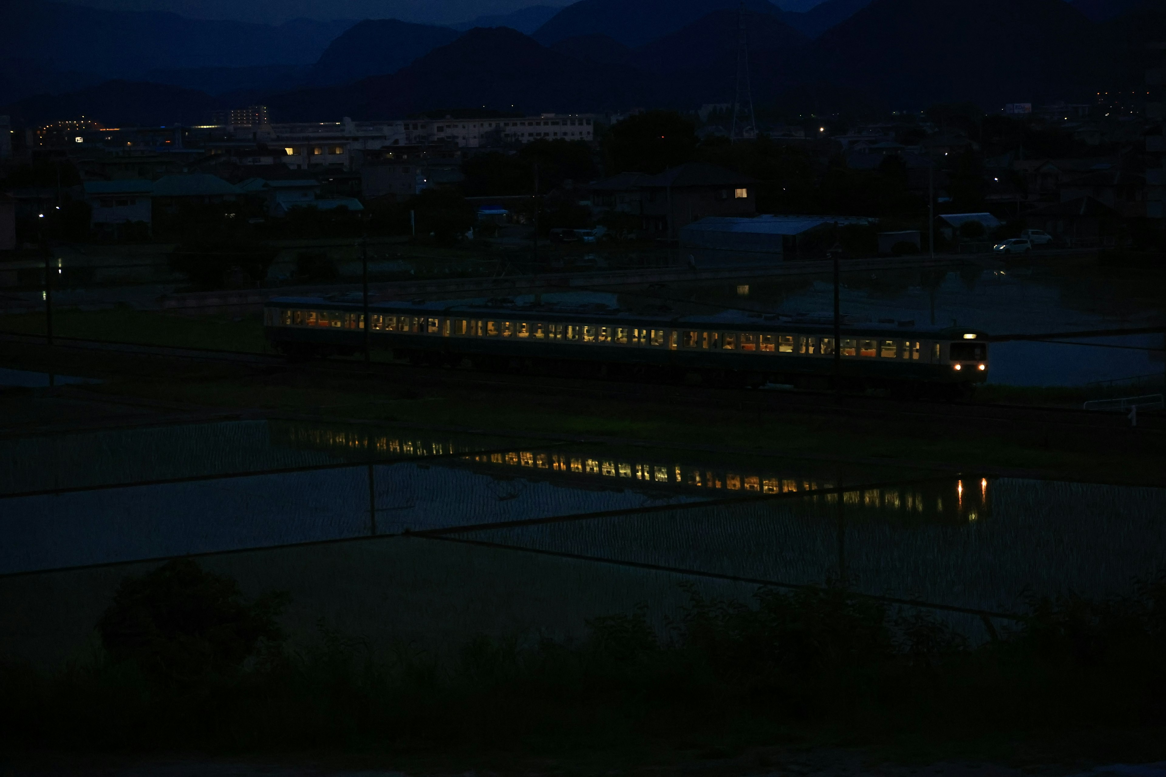 Luci del treno che si riflettono in un paesaggio rurale scuro