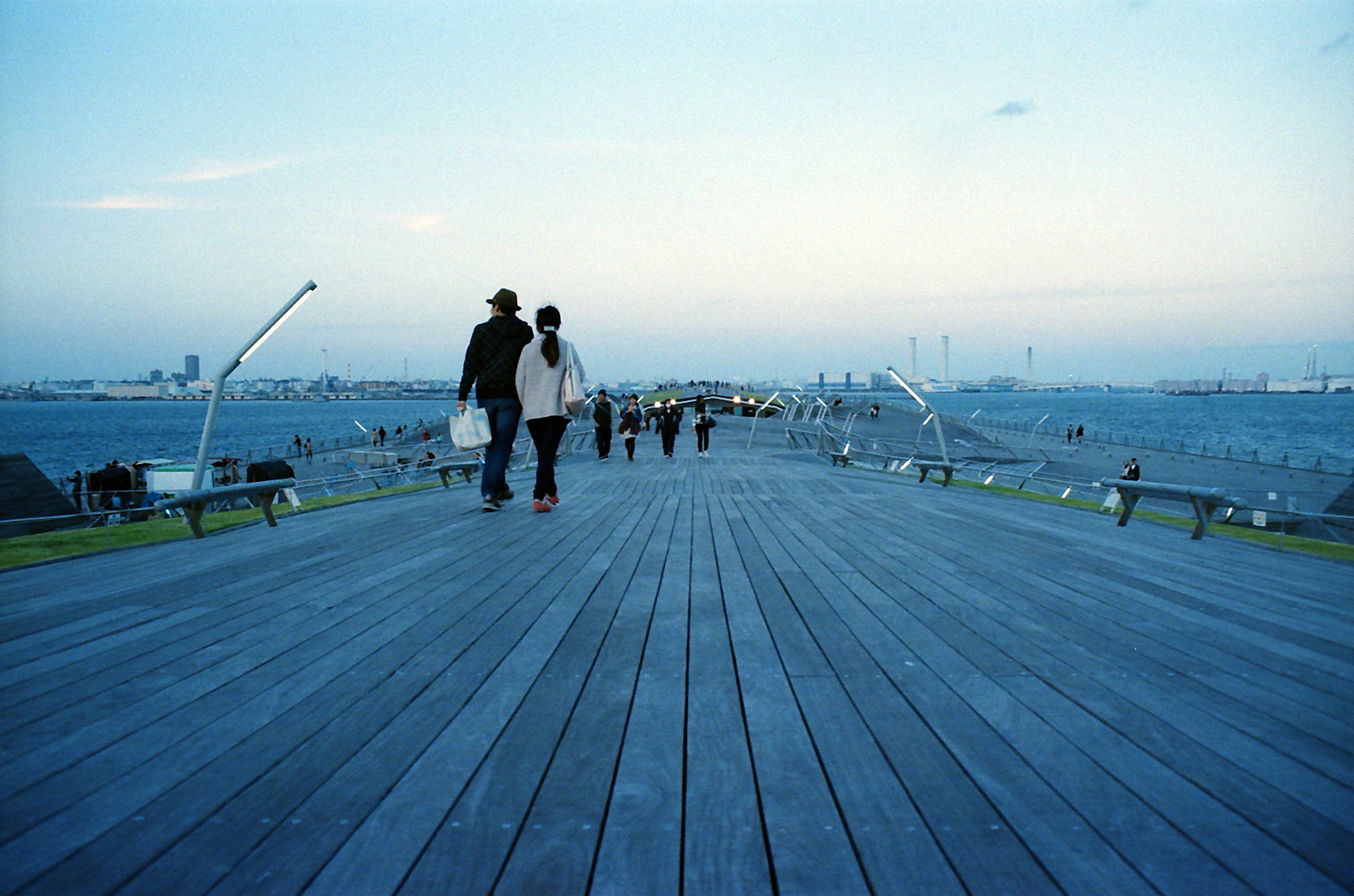 Silhouettes of people walking on a wooden deck at dusk