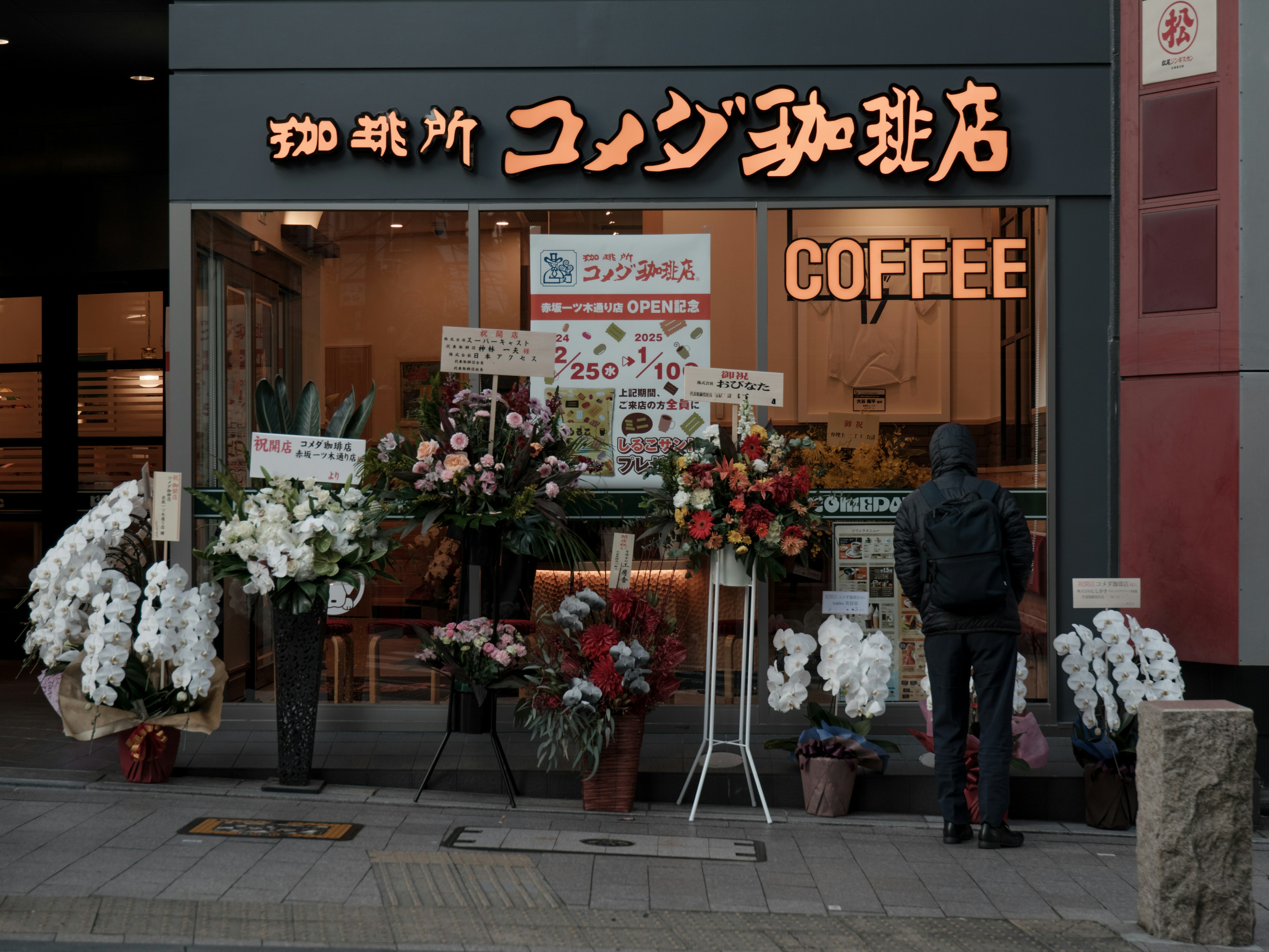 Außenansicht eines blumenverzierten Cafés mit Beschilderung