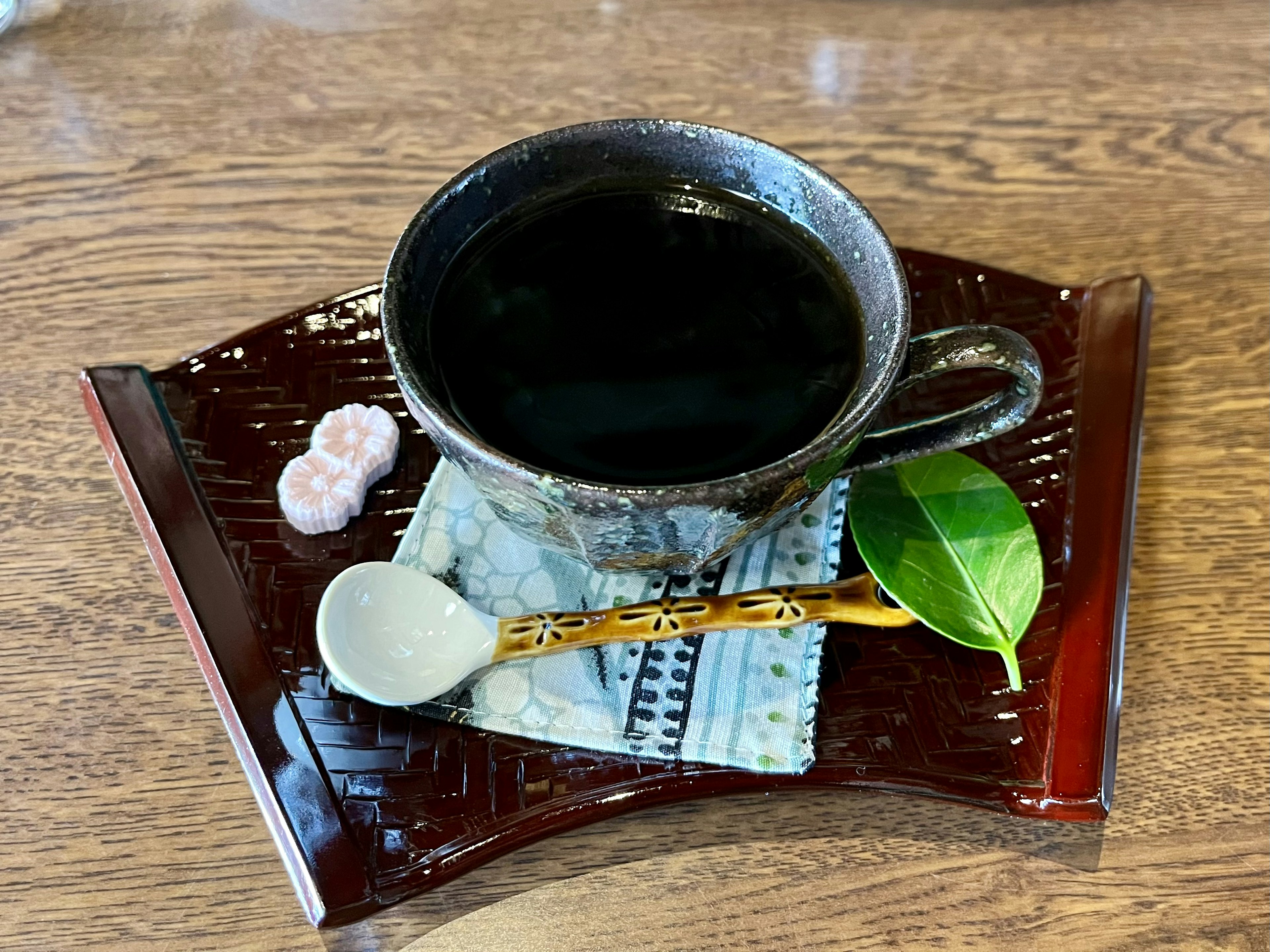 黒いお茶が入ったカップと茶葉の葉があるお皿