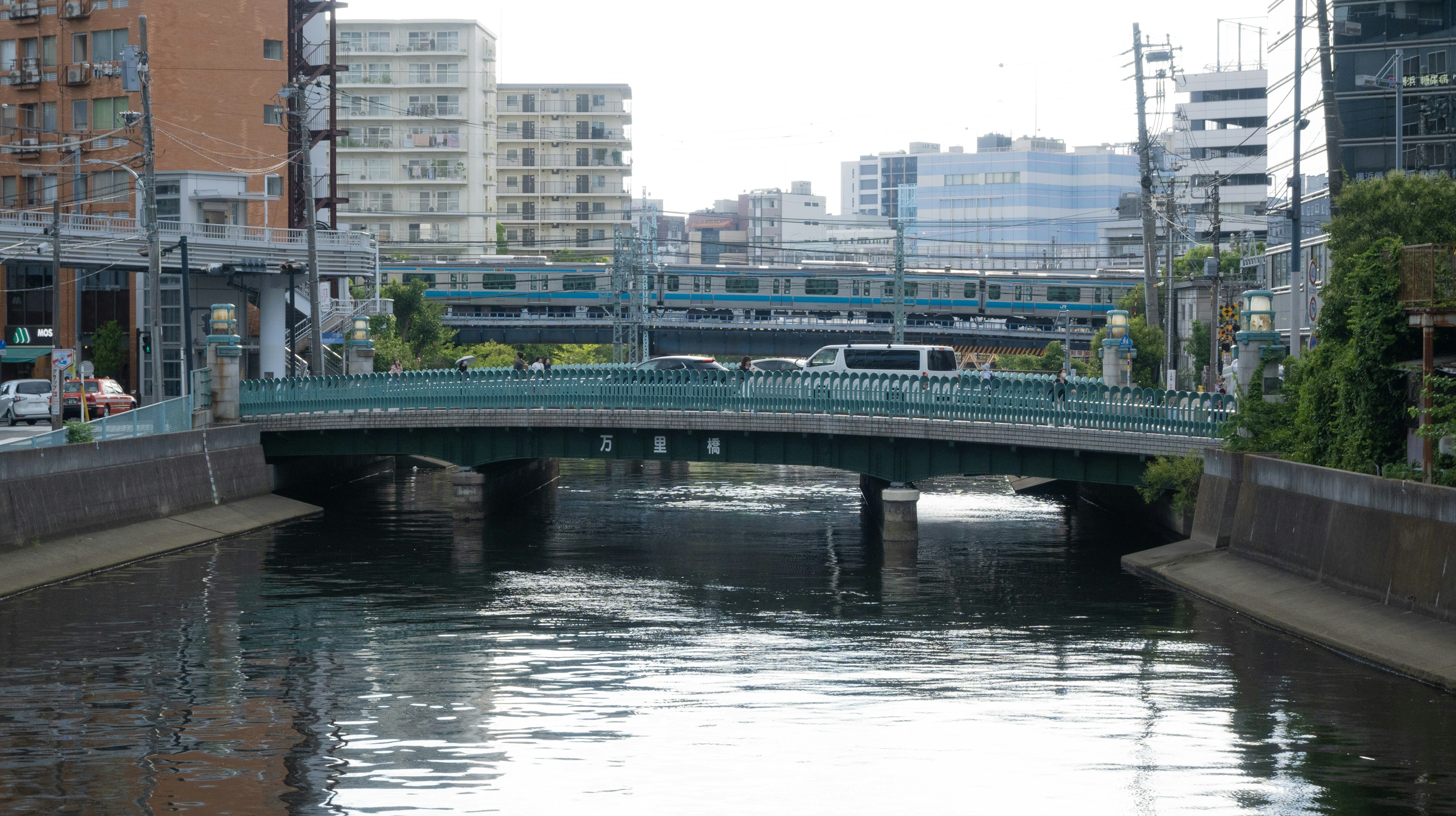 Ponte verde su un fiume calmo con edifici urbani sullo sfondo