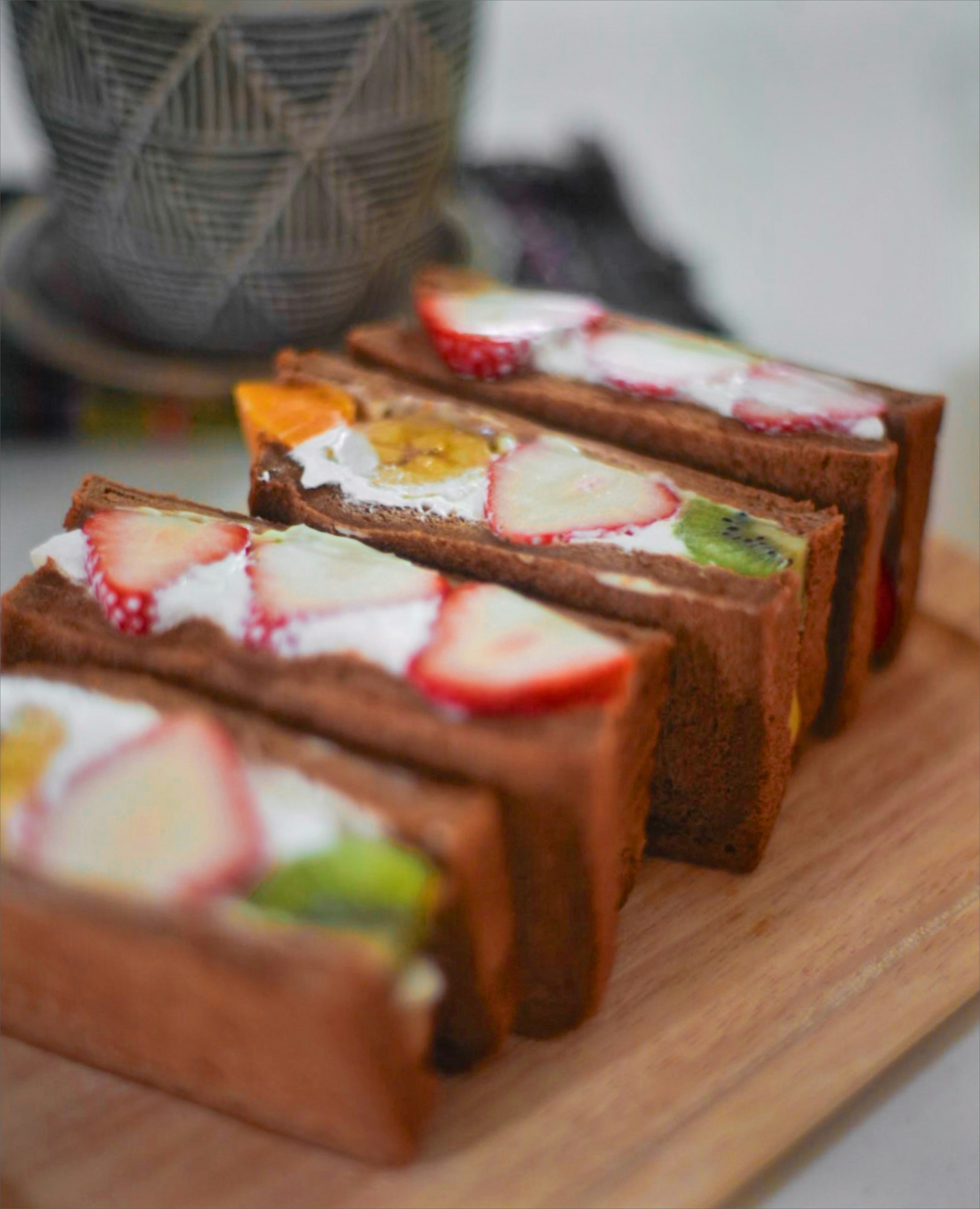 Slices of layered fruit and cream dessert arranged on a wooden board