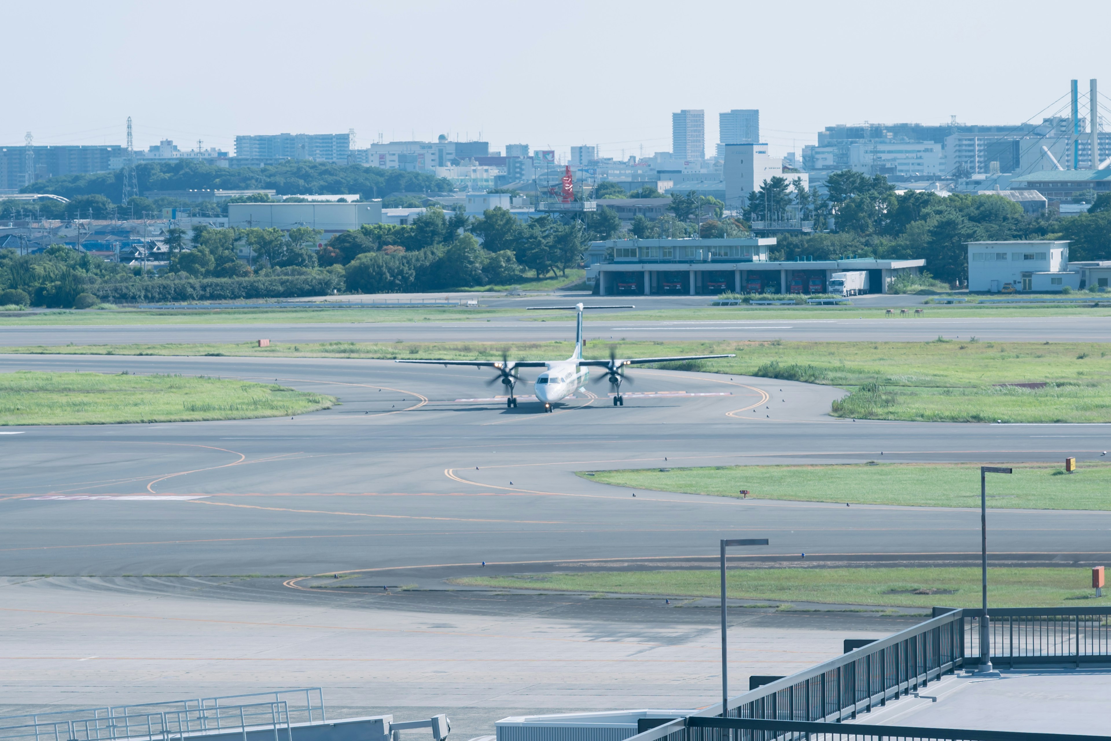 空港で滑走路にいる小型飛行機と周囲の都市の景色