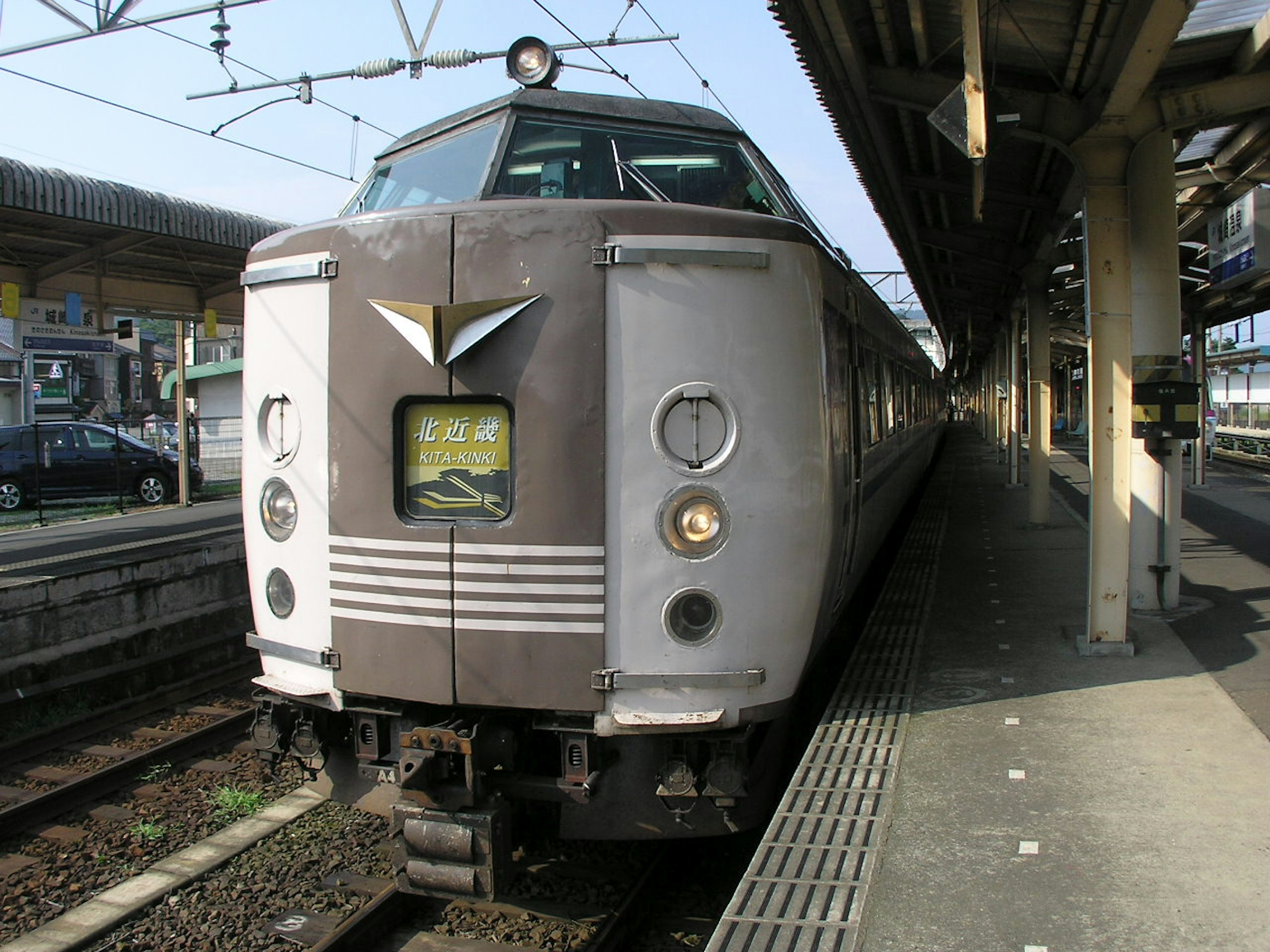 Un treno di vecchio stile fermo in stazione con una carrozzeria argentata e un design anteriore distintivo