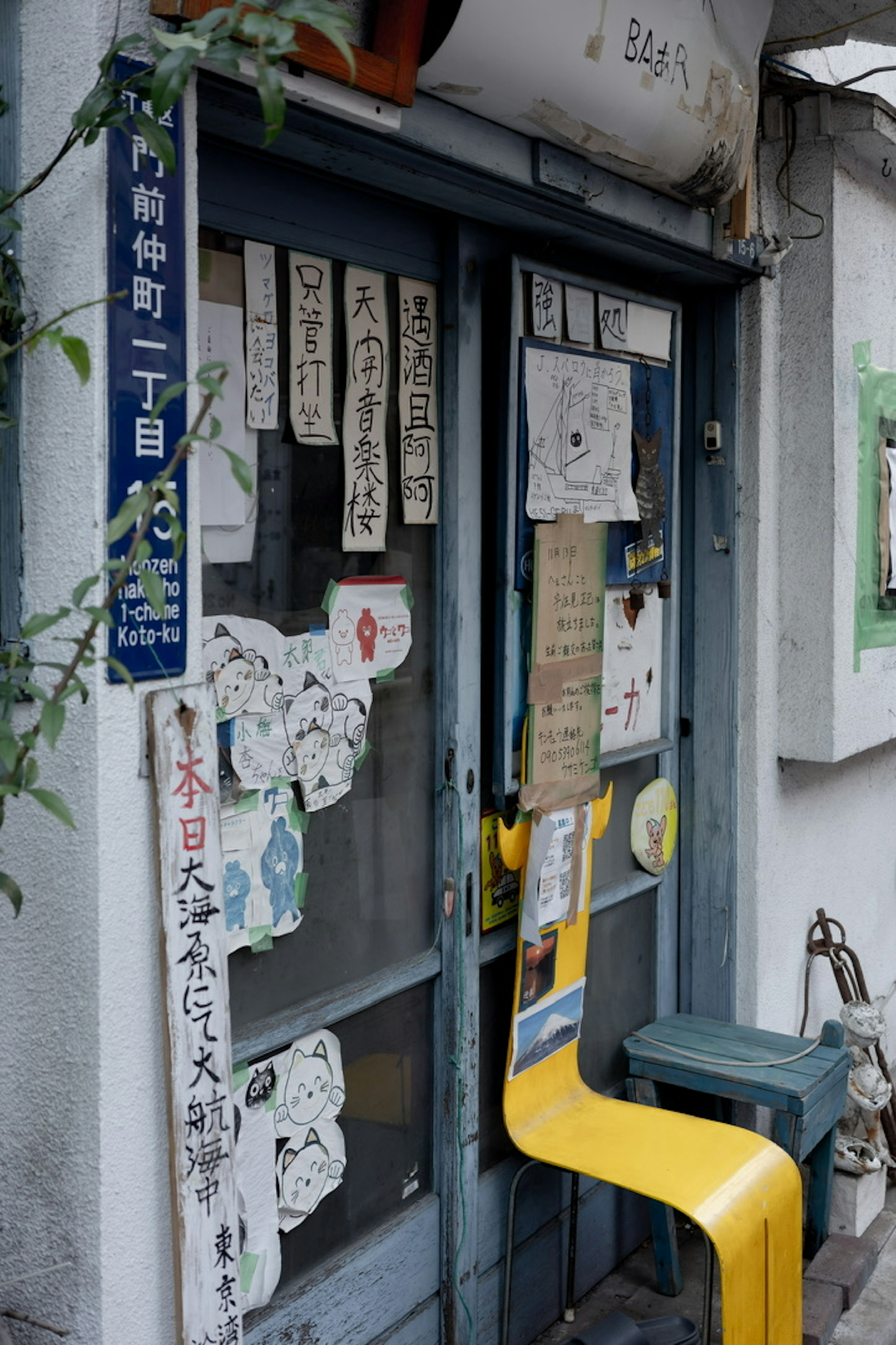 ภายนอกของร้านค้าที่มีประตูสีน้ำเงินเต็มไปด้วยโน้ตและโปสเตอร์