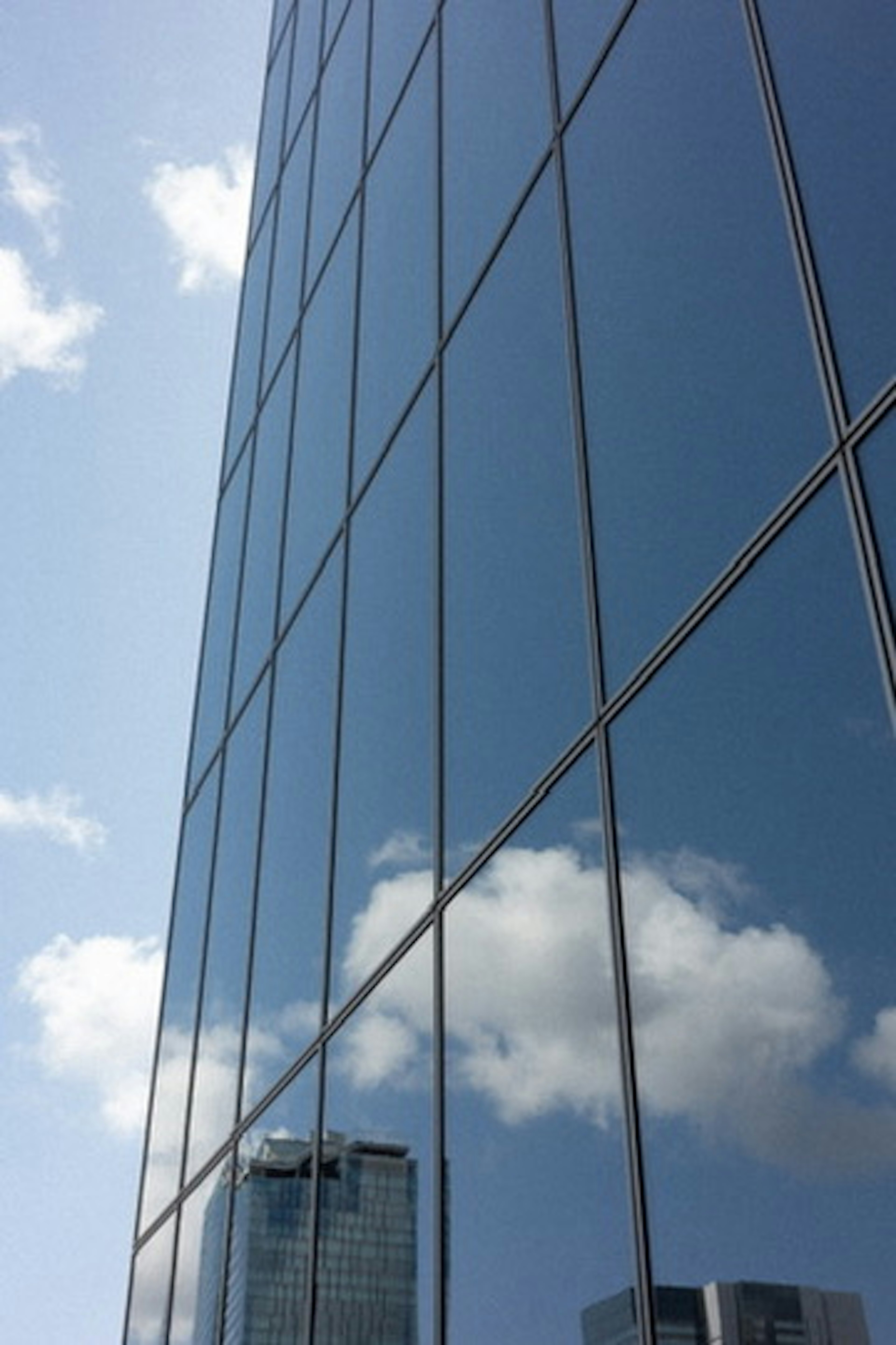 Reflejo del cielo y las nubes en la fachada de vidrio de un edificio