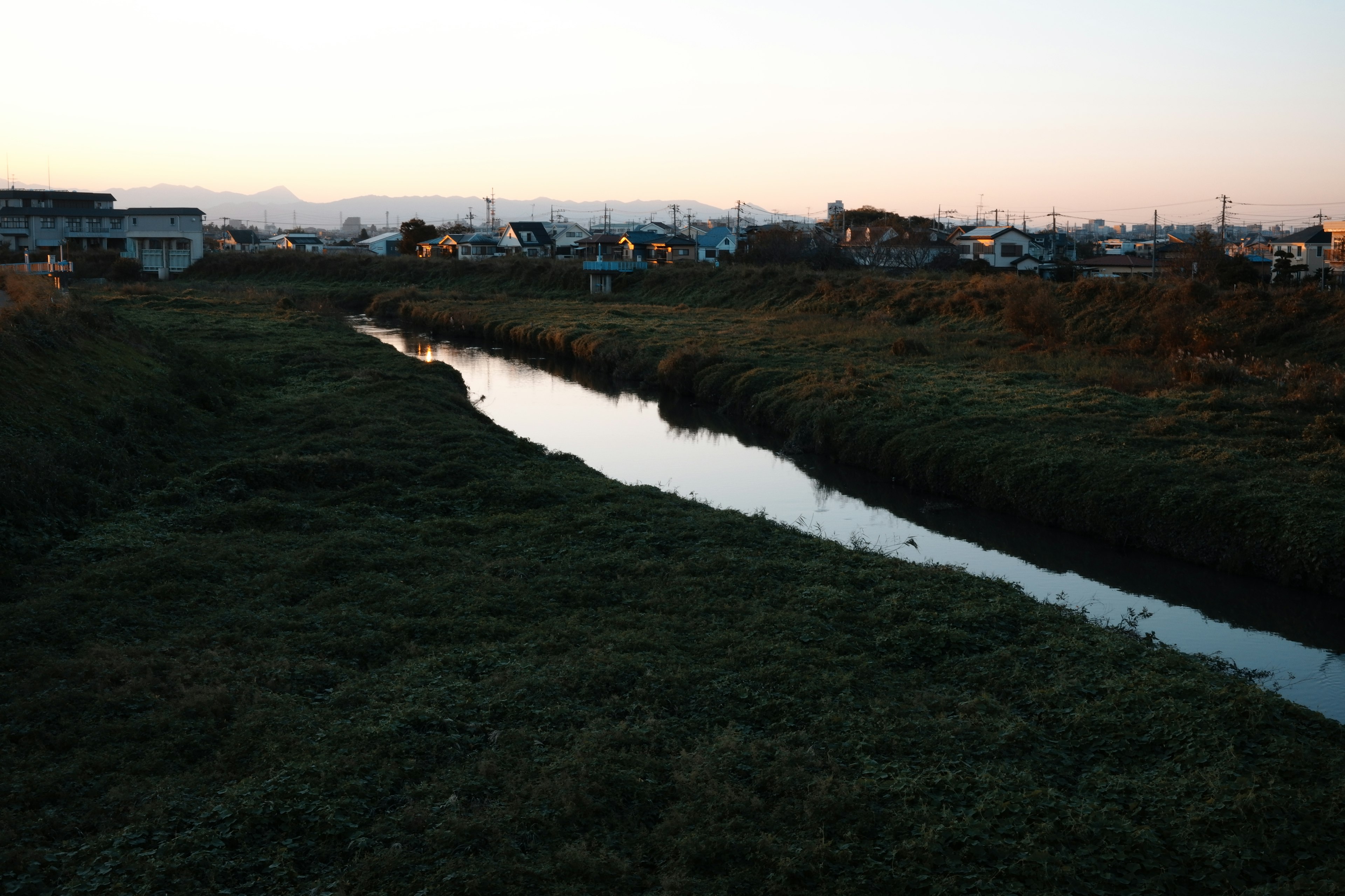 静かな川の流れと周囲の草地の風景