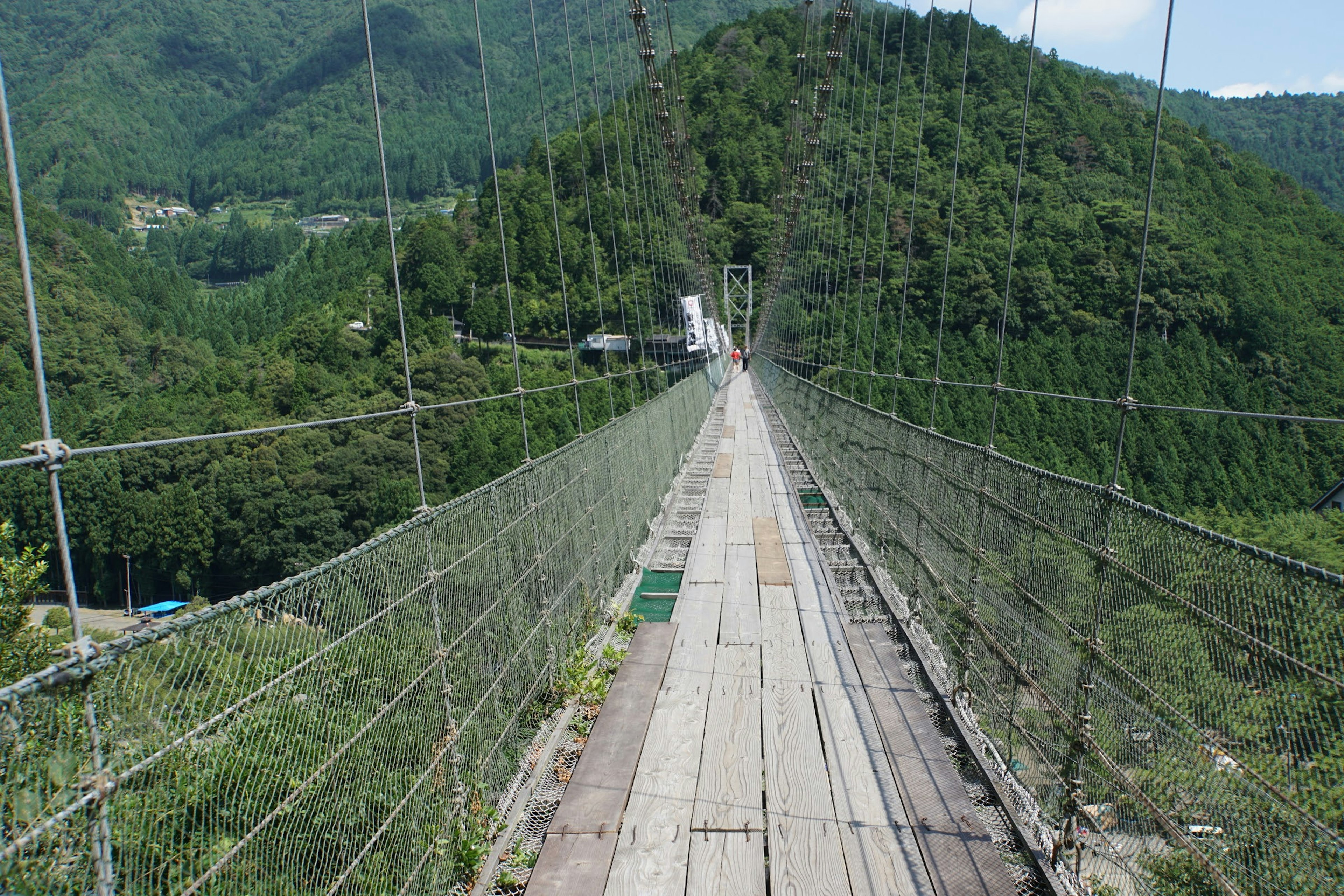 วิวสะพานแขวนที่มีภูเขาสีเขียวในพื้นหลัง