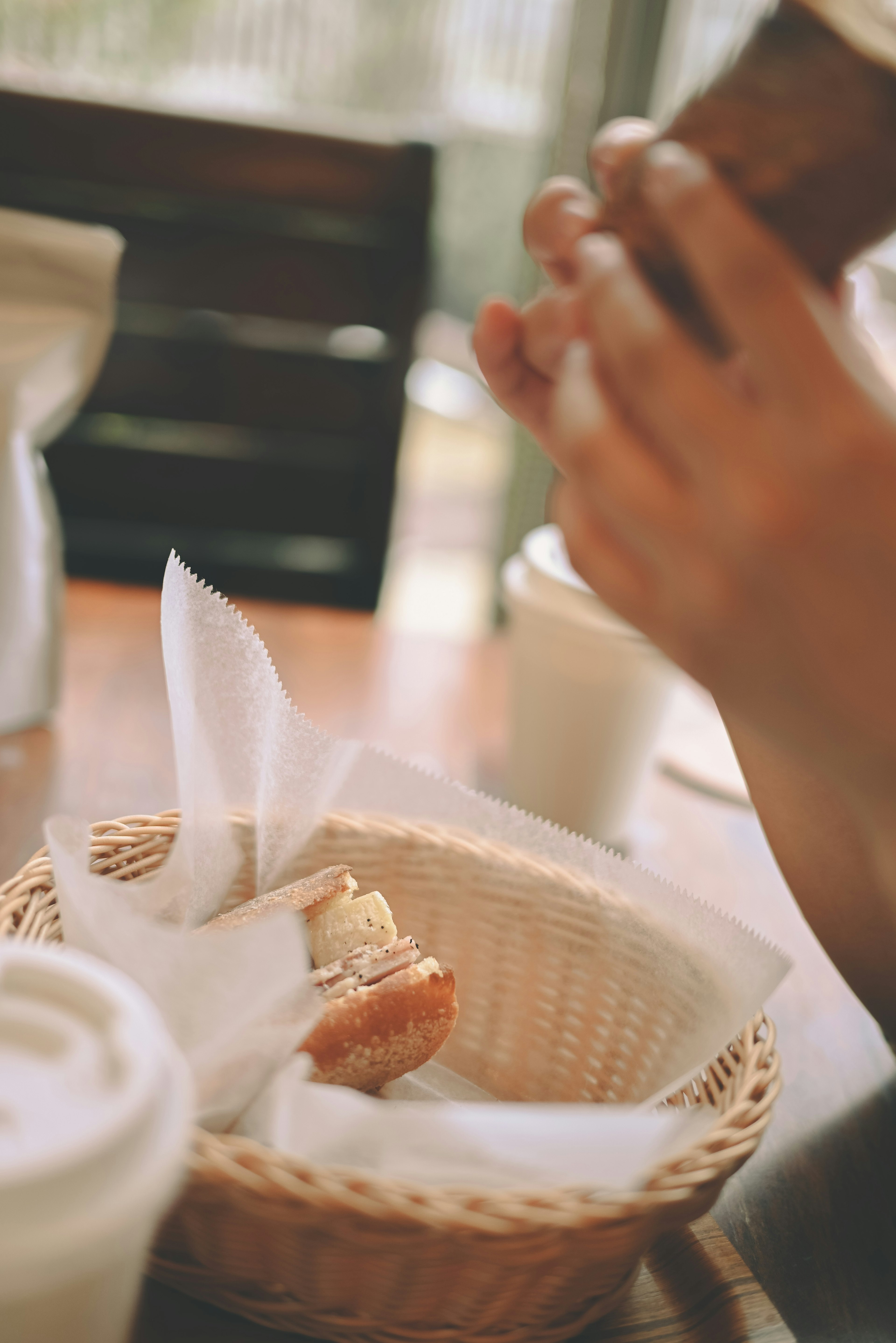 Une main tenant un appareil photo au-dessus d'un panier de pain sur une table de café