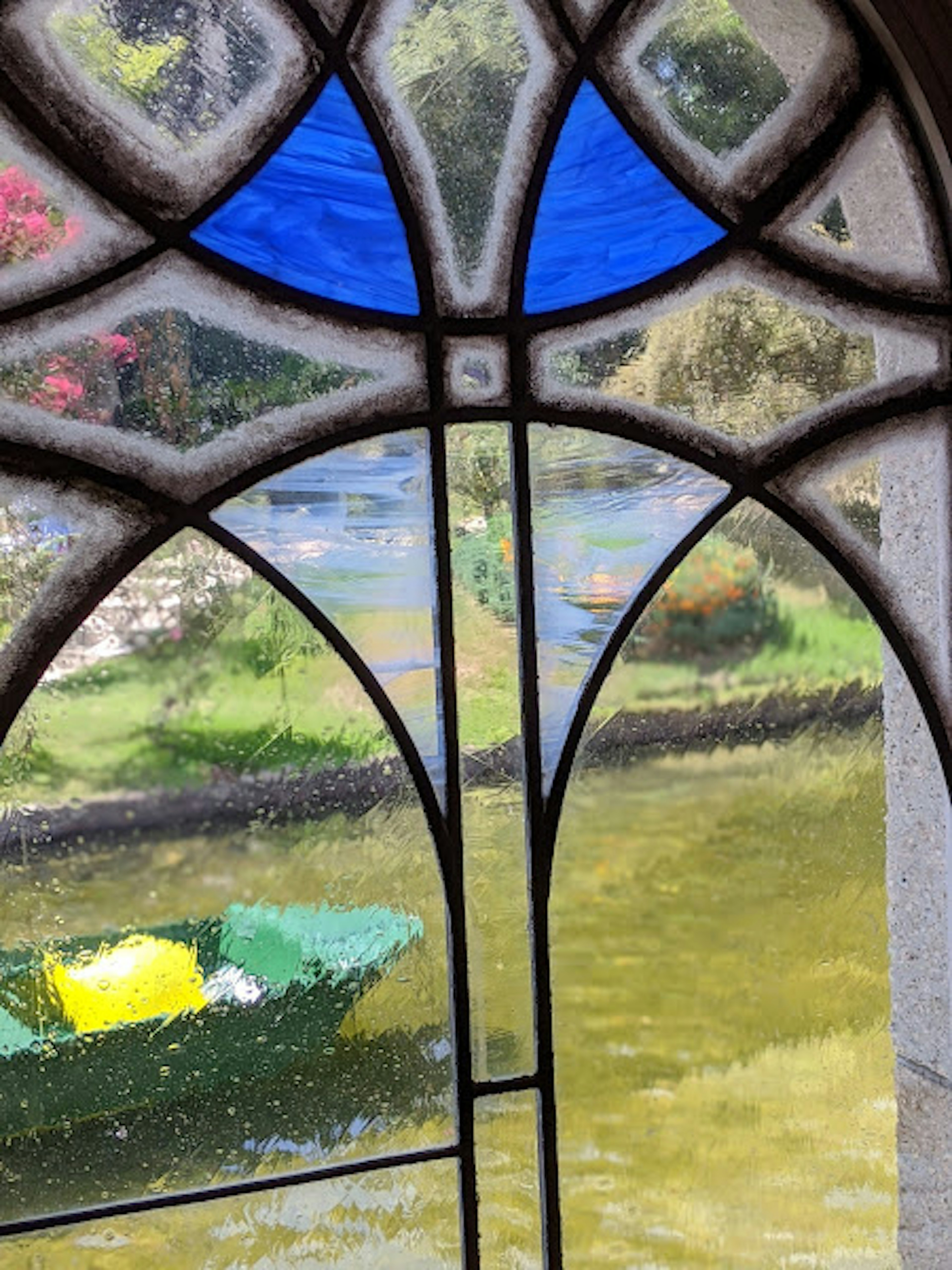 Blick auf ein grünes Boot und Wasserszenerie durch ein Buntglasfenster