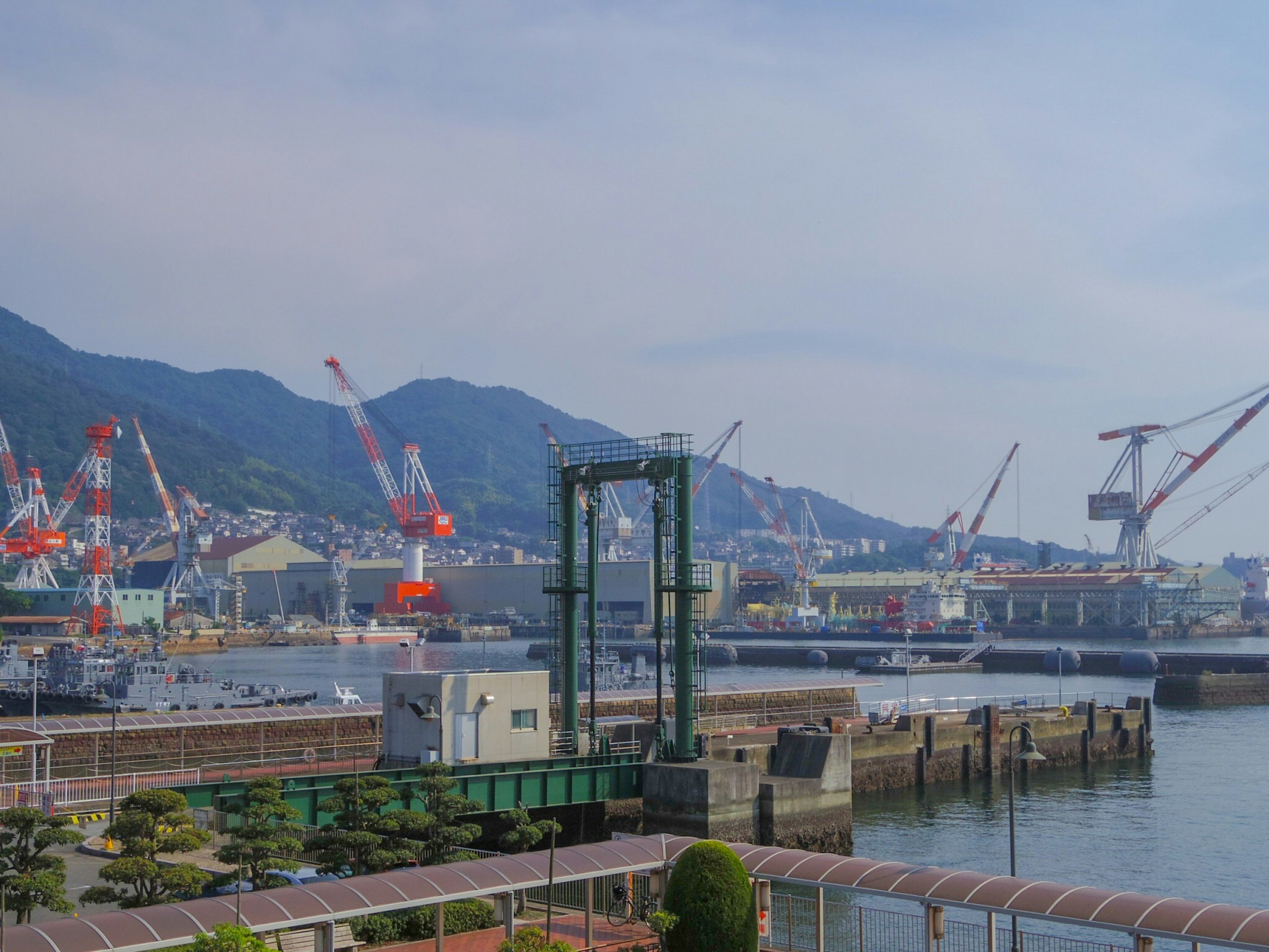 Landscape featuring cranes at a port with mountains in the background