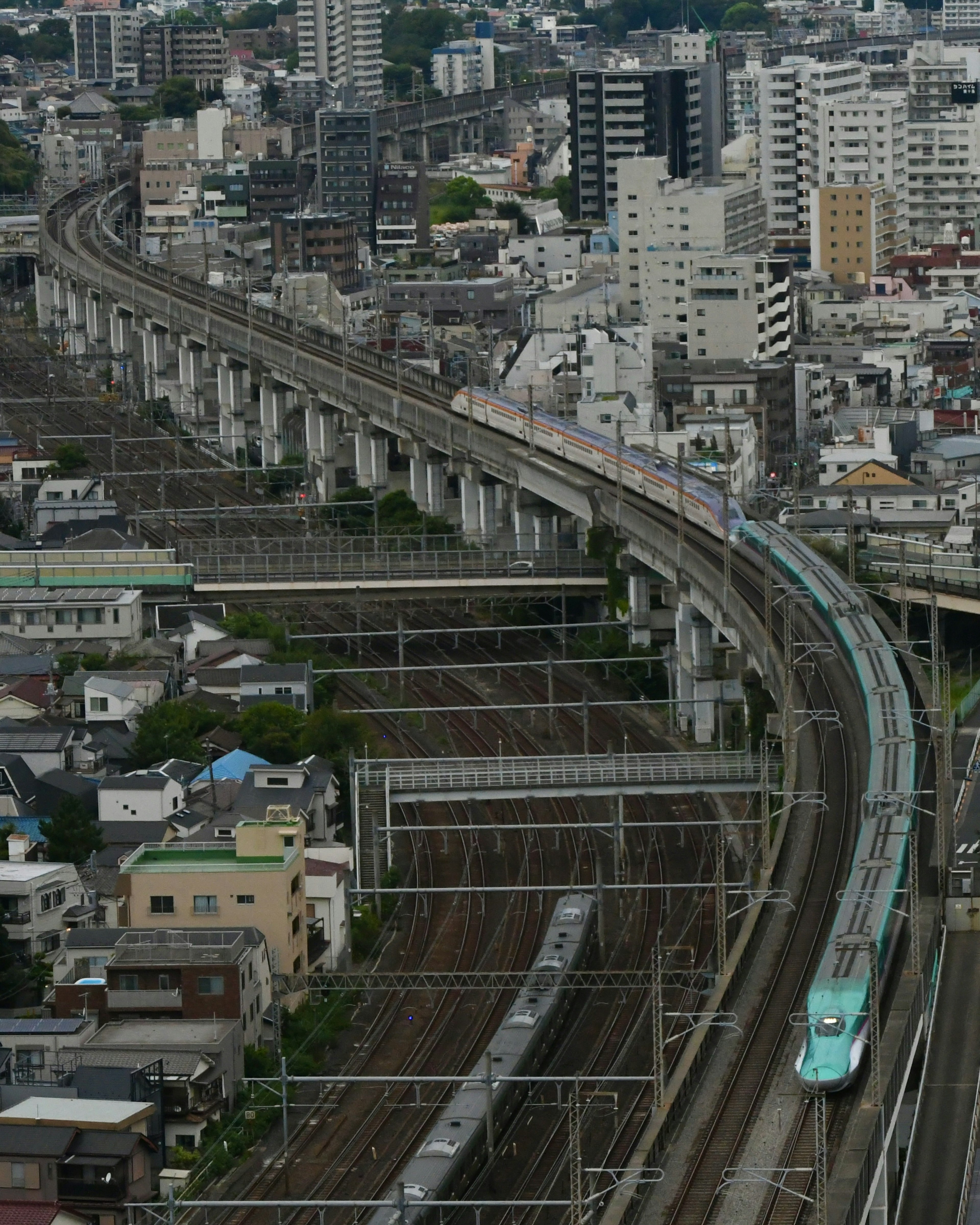 都市の風景を背景に走る電車と曲がりくねった線路