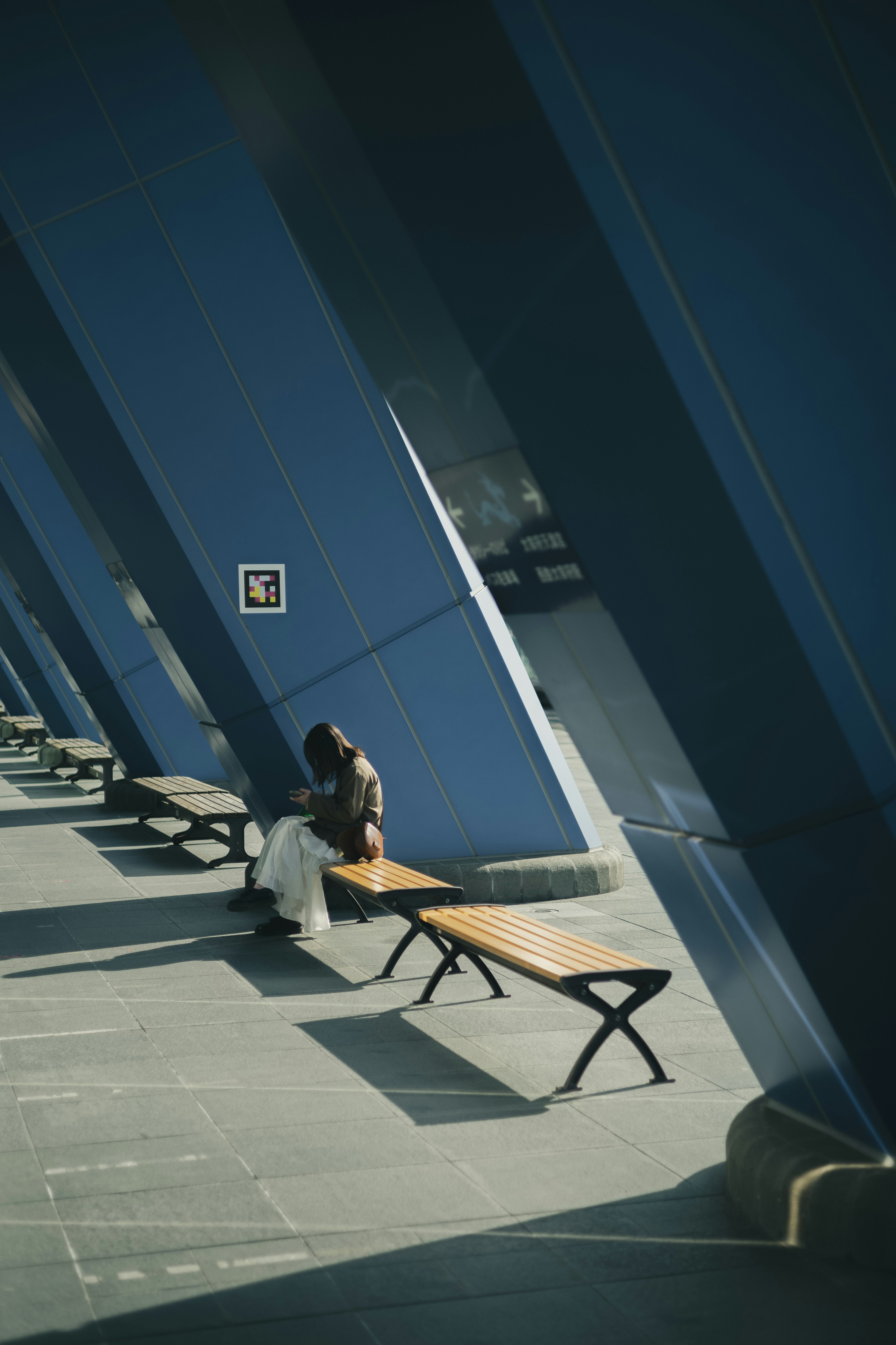 Une personne assise sur un banc dans un espace moderne avec des murs bleus