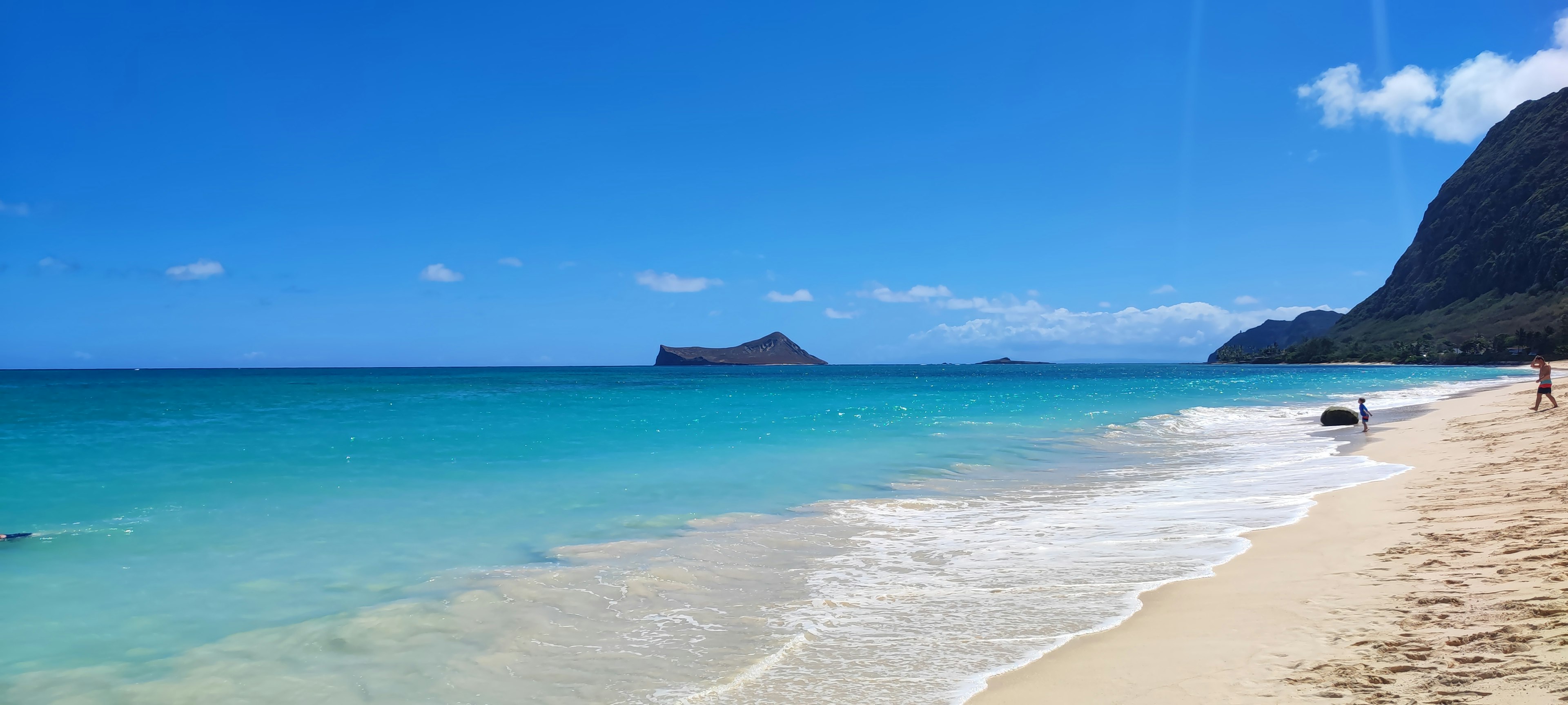 ทิวทัศน์ชายหาดที่มีน้ำทะเลสีฟ้าและทรายขาว