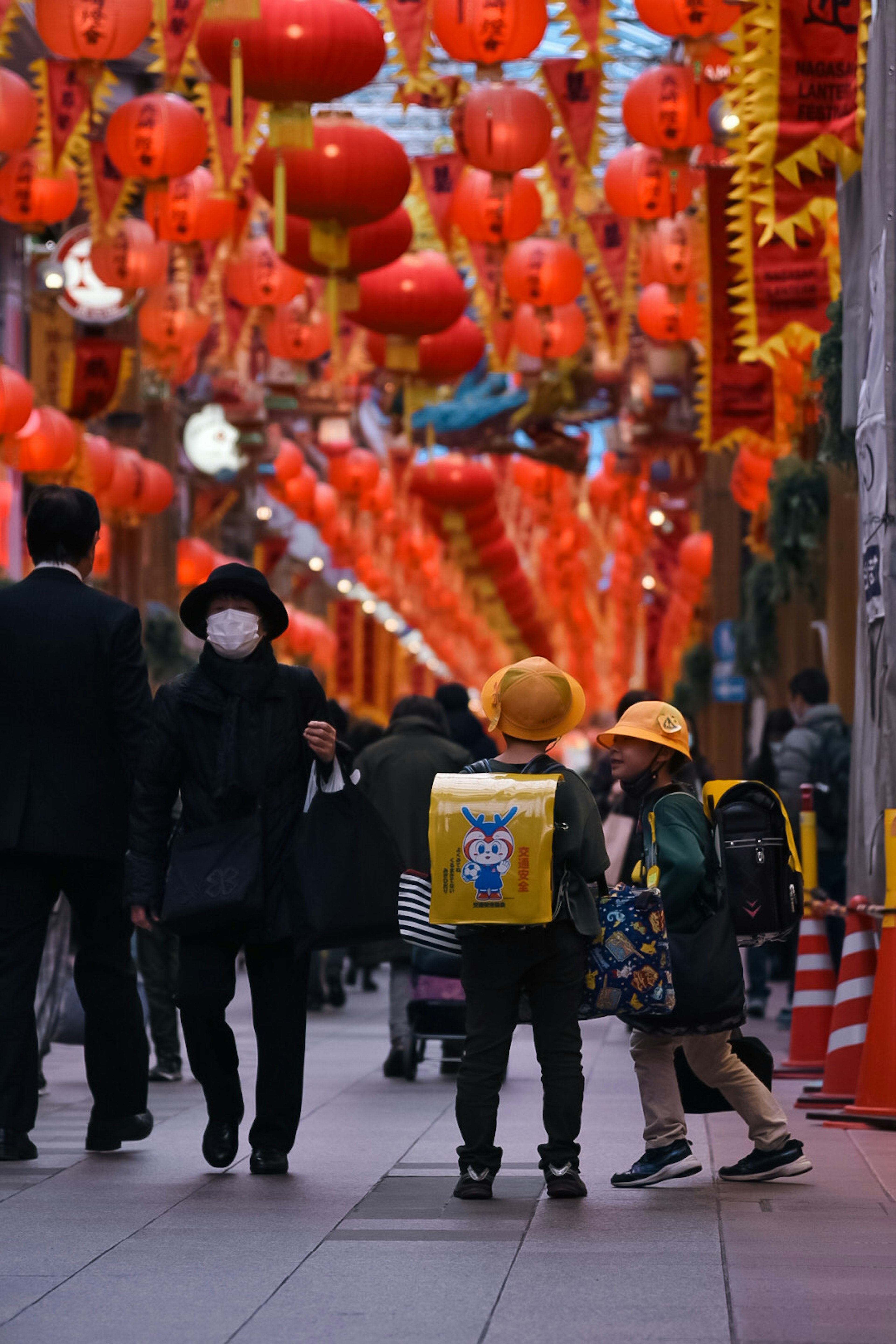 孩子們在裝飾著紅燈籠的街道上玩耍，成年人路過