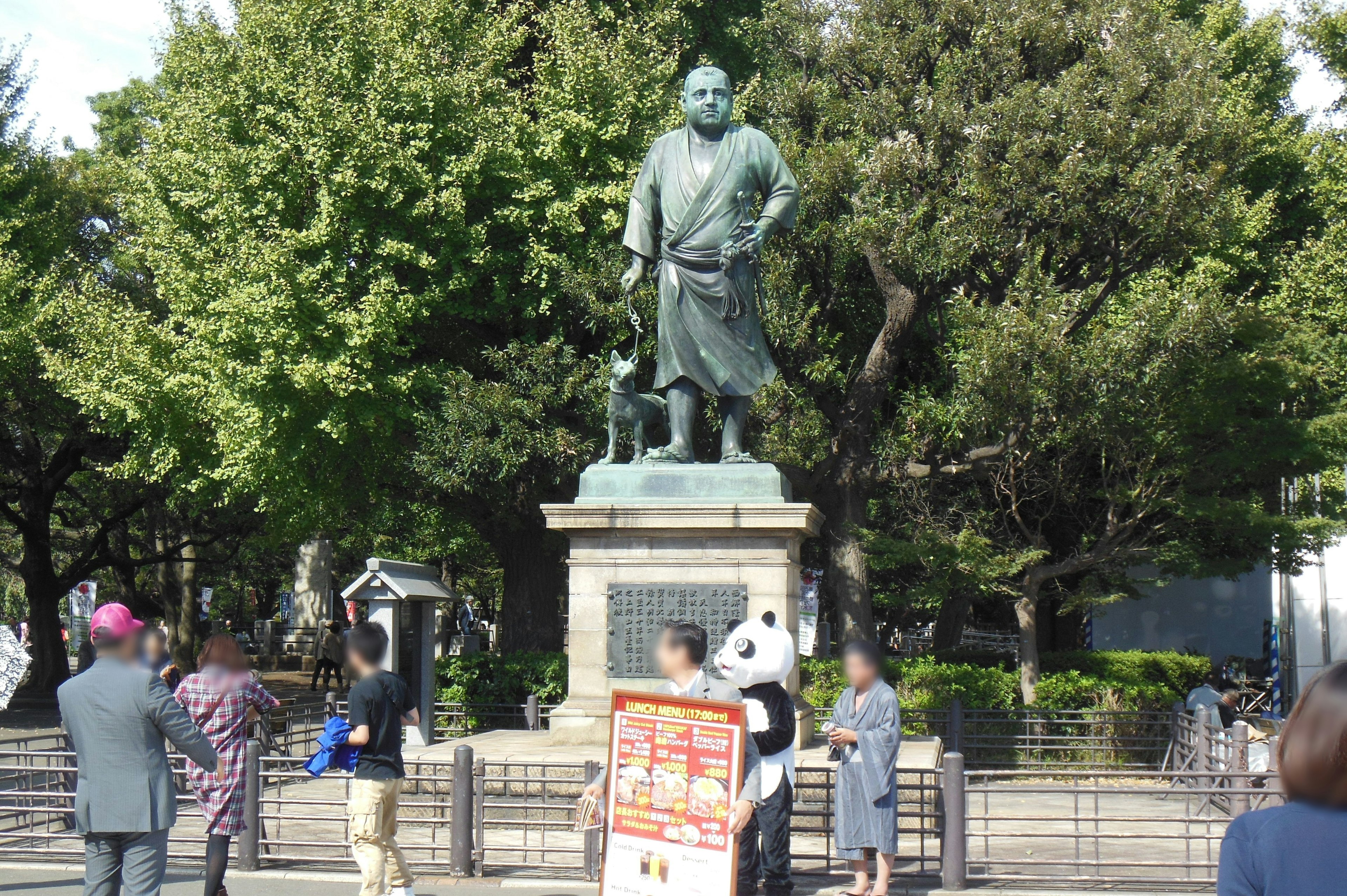 公園に立つ歴史的な銅像と周囲の人々