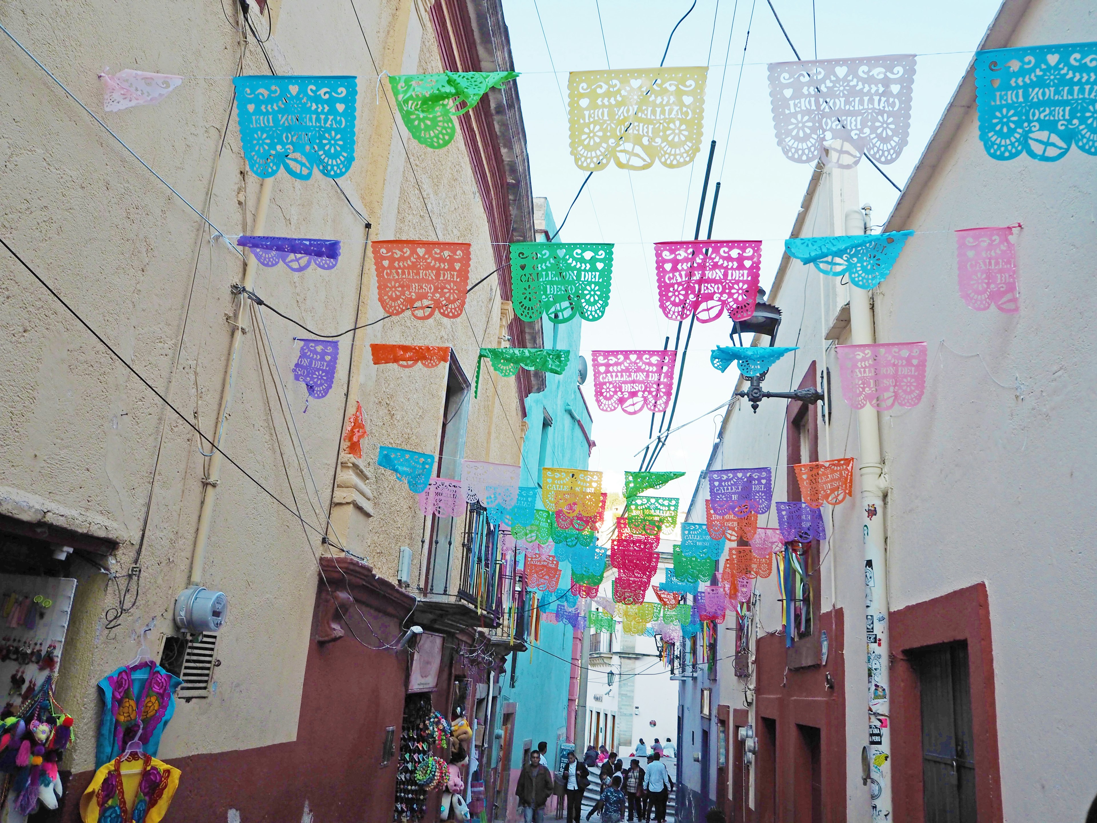 Banderas de papel picado coloridas colgando sobre una escena callejera vibrante