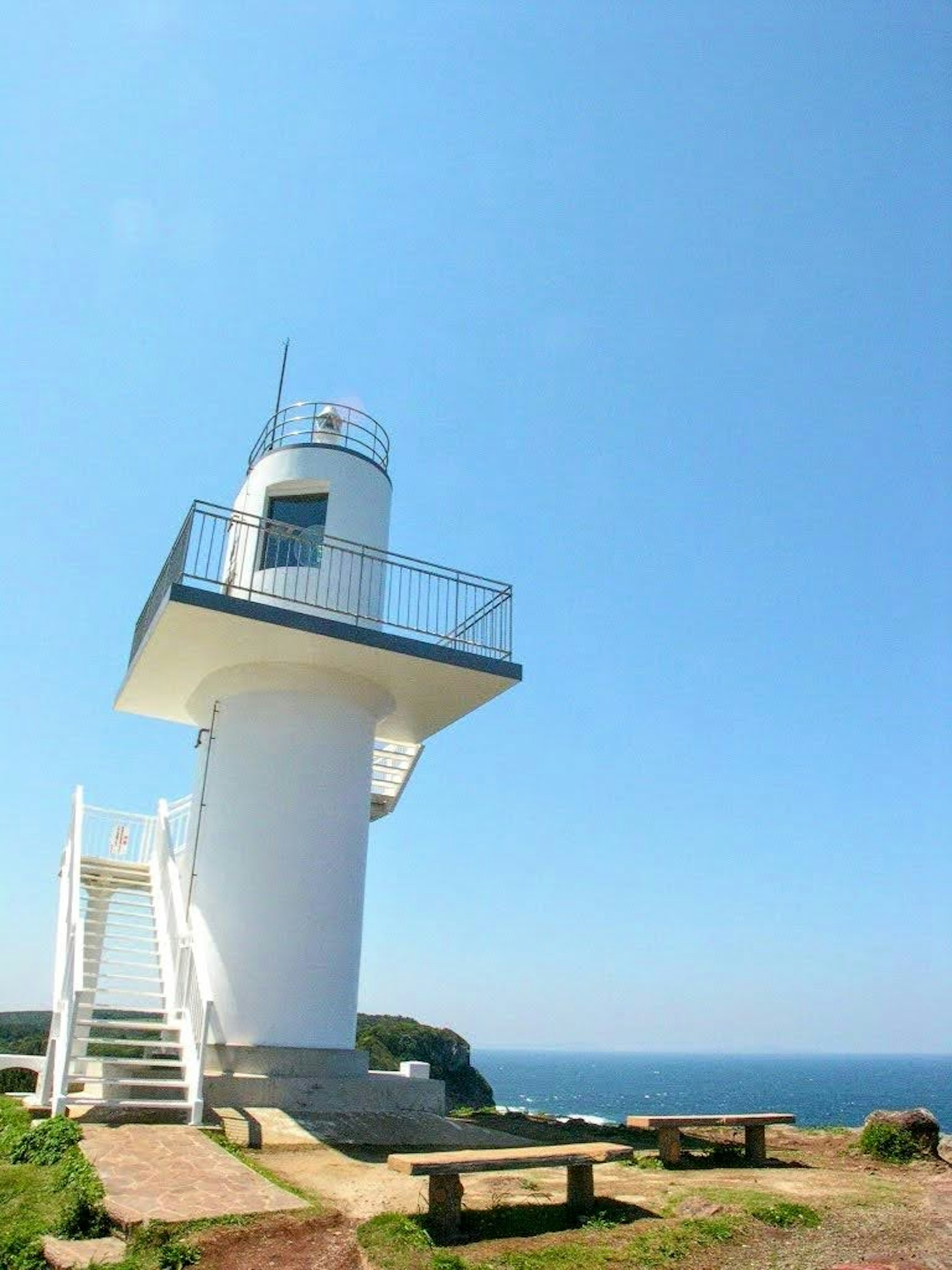 白い灯台が青い空の下に立っている