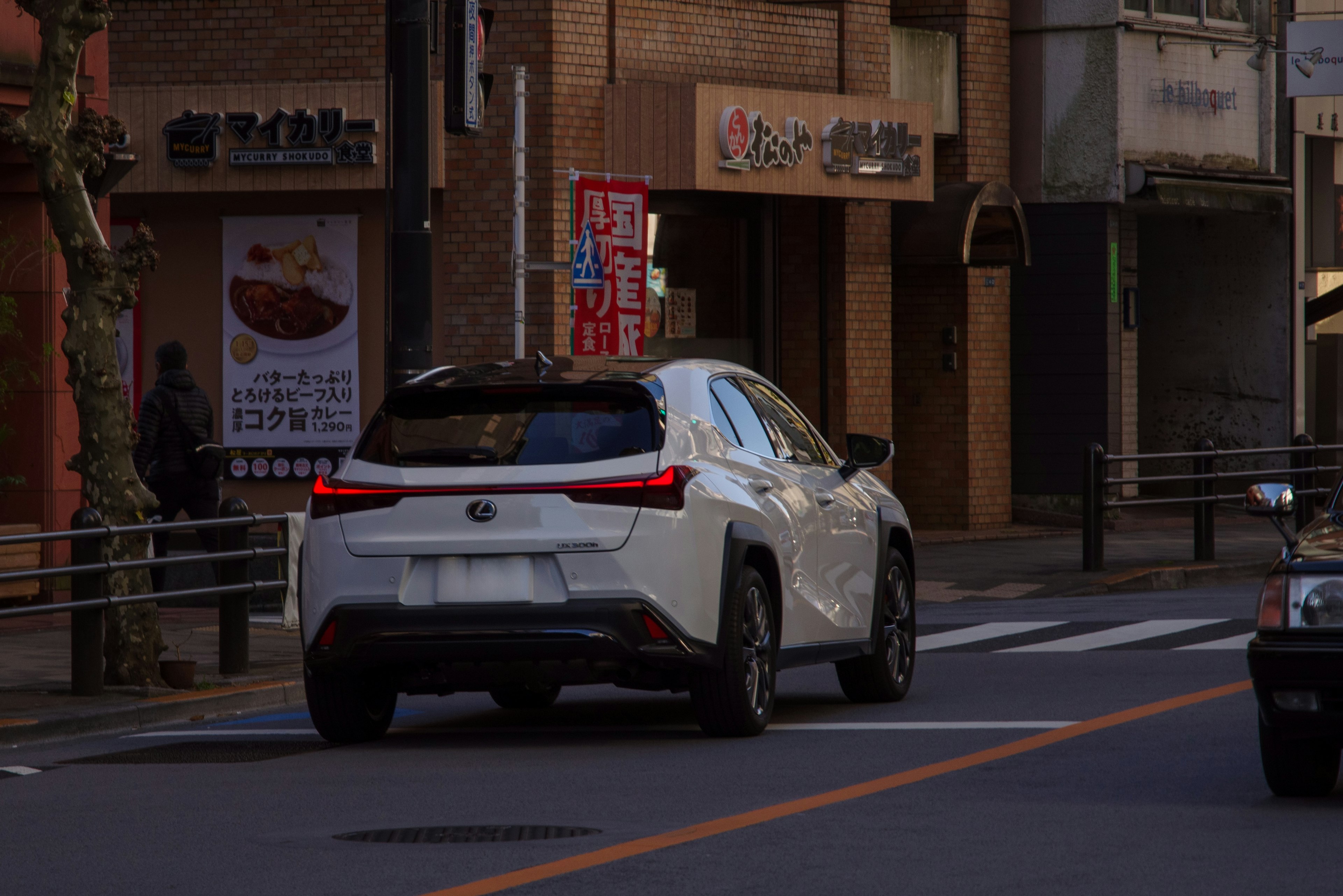 A white SUV driving on a city street with restaurant signage in the background