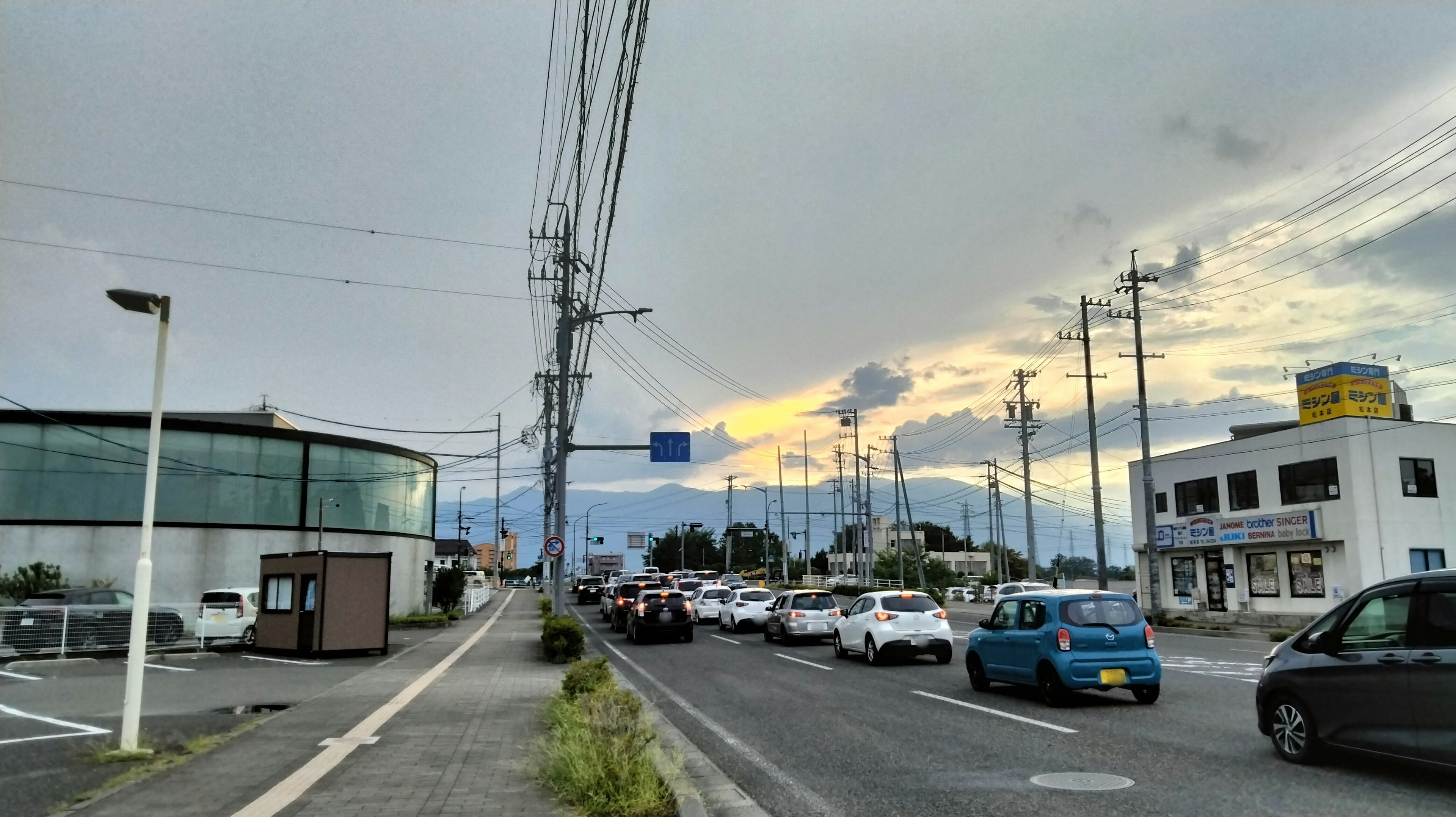 道路と建物が並ぶ風景 晴れた空に雲が広がり 山々が遠くに見える