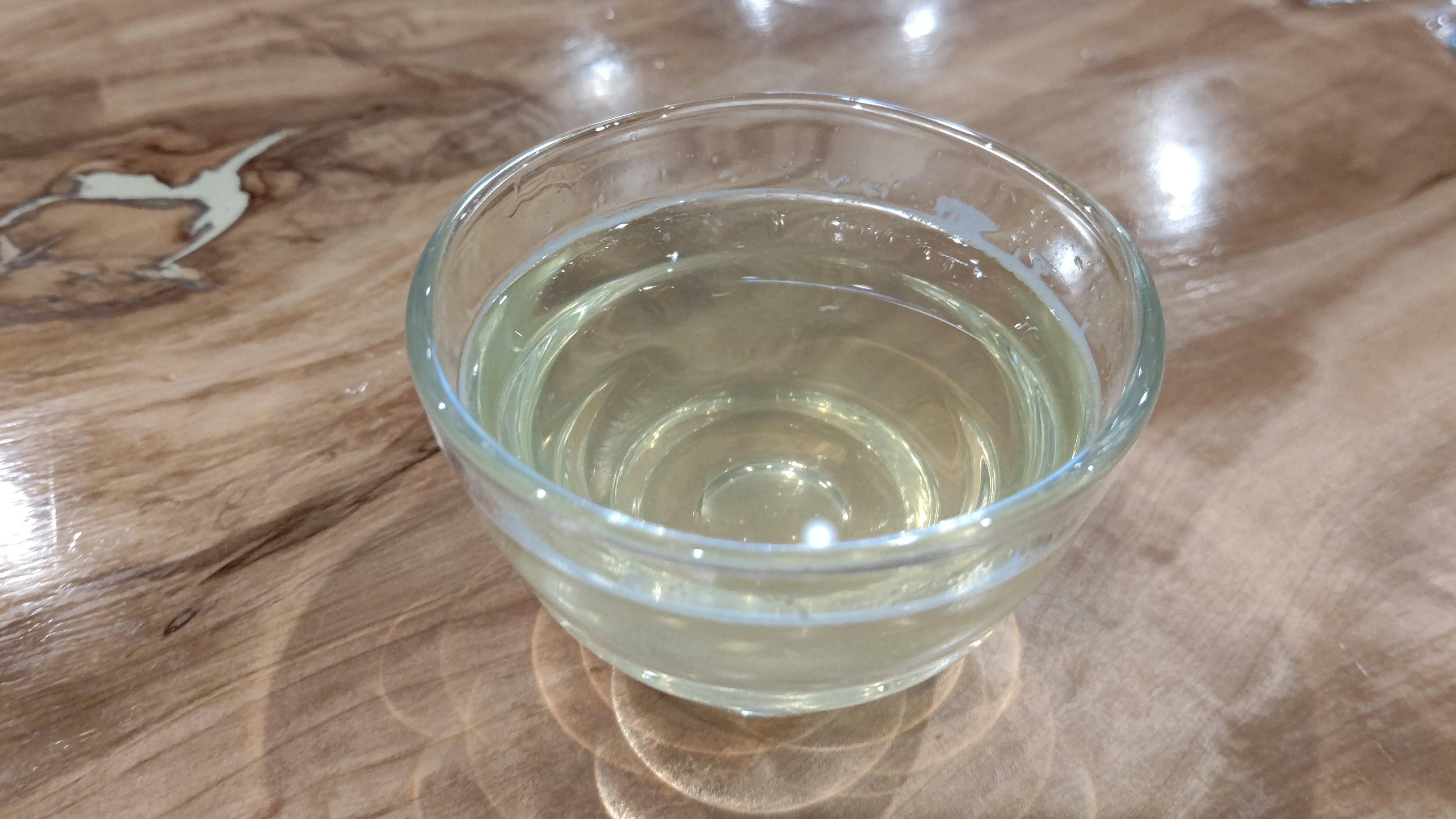 A glass bowl containing a clear liquid placed on a wooden table