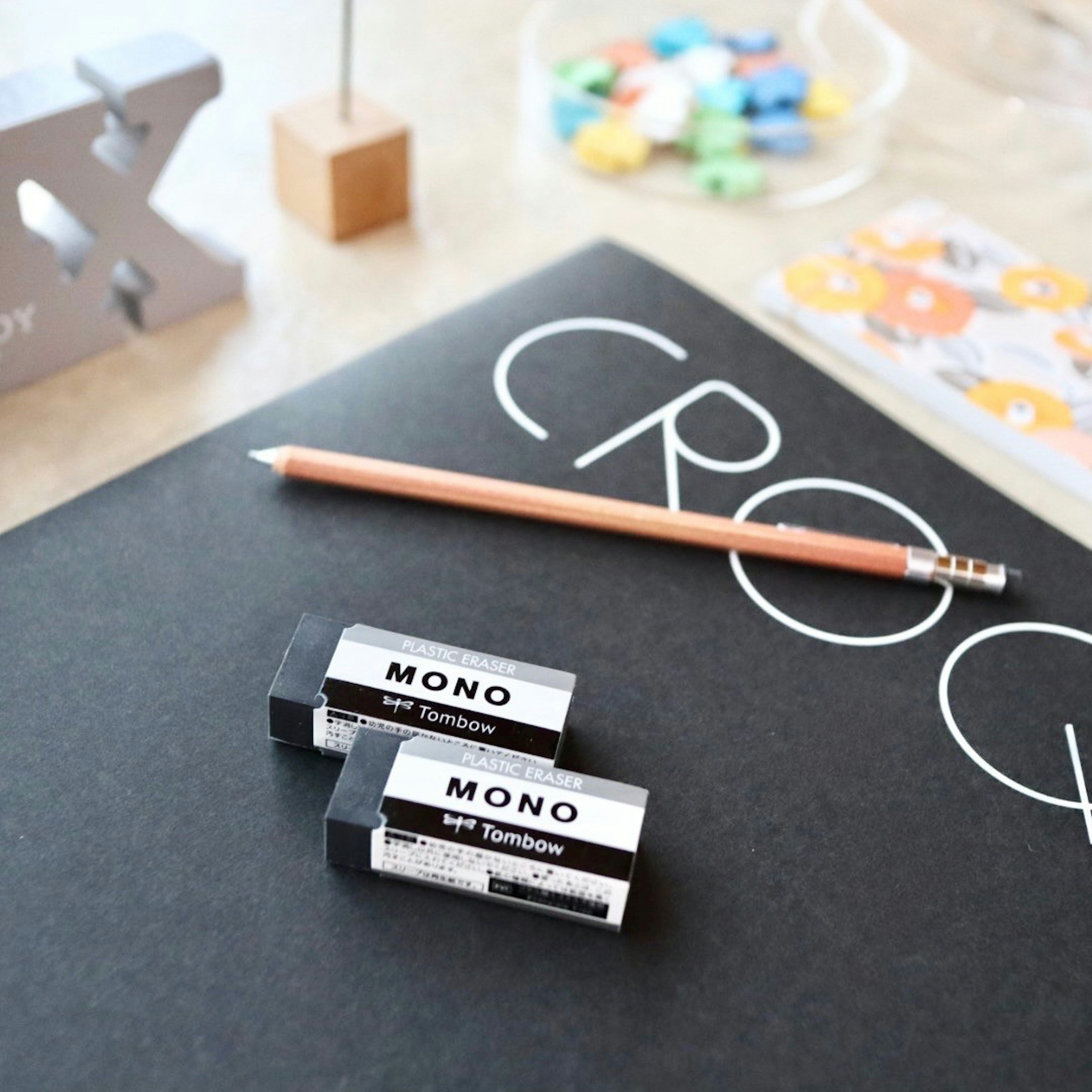 Image of MONO erasers and a pencil on a black notebook