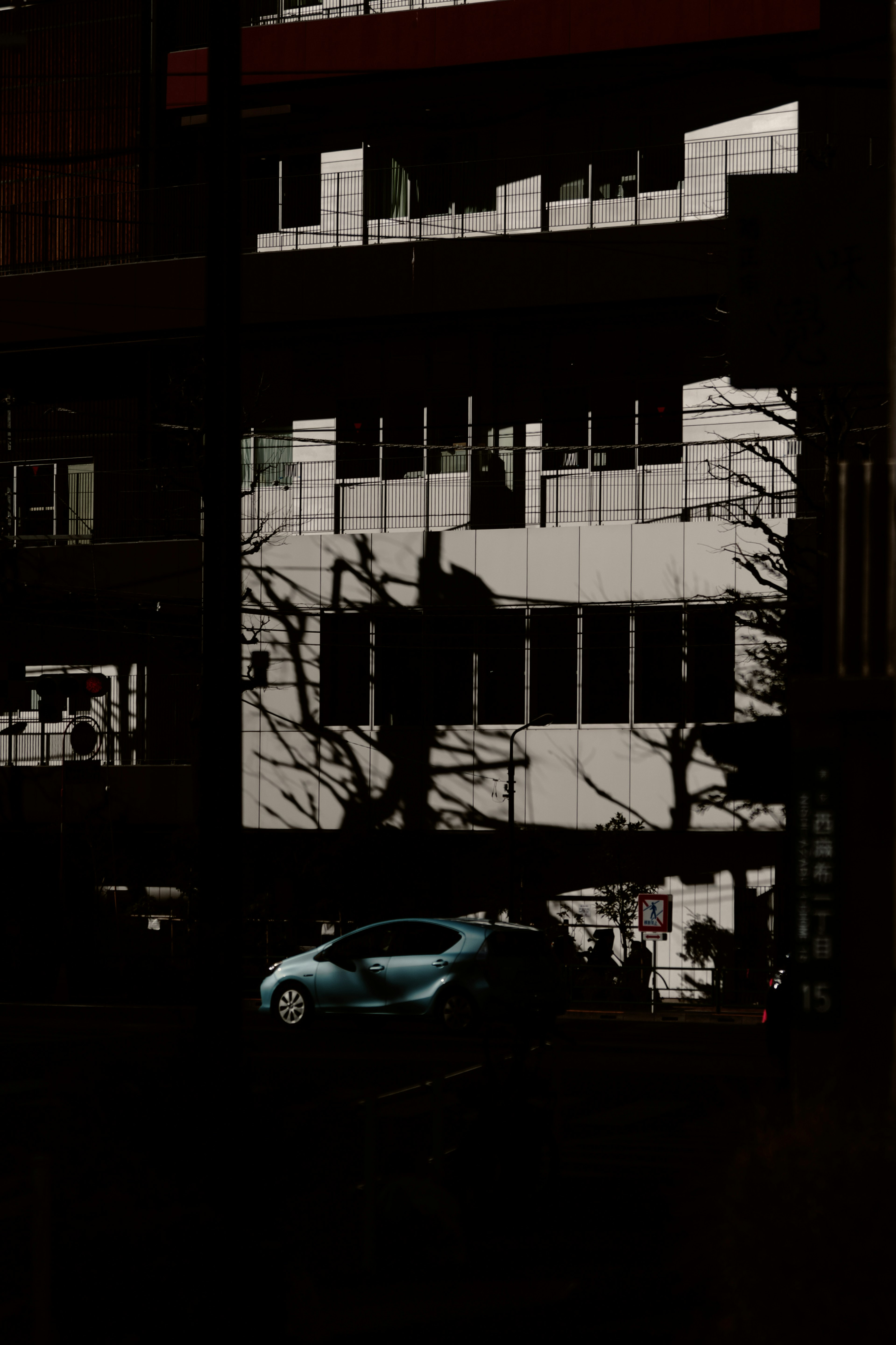 Ombres de bâtiment avec une voiture bleue réfléchie dans un environnement sombre