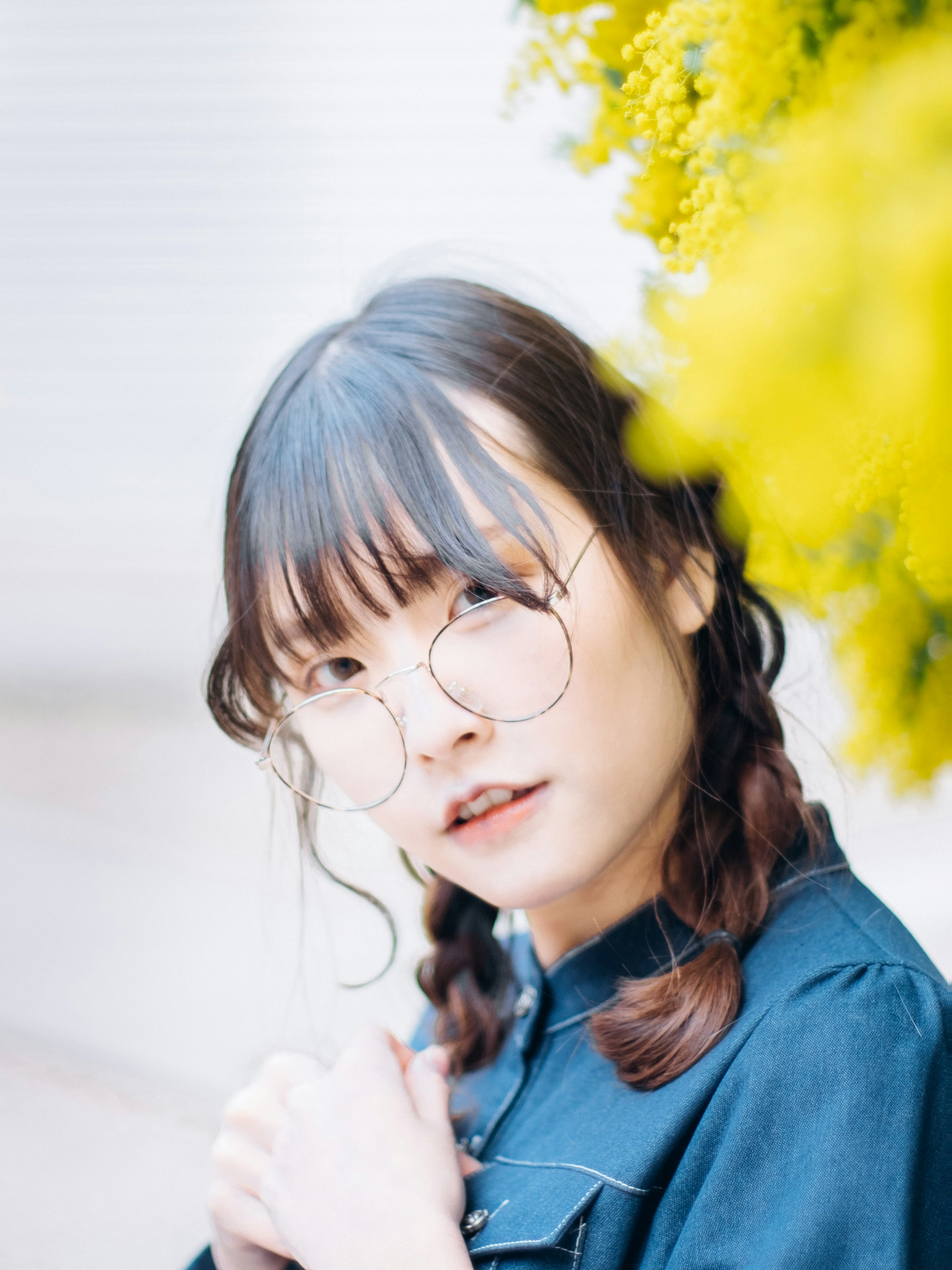 Jeune femme avec des lunettes posant devant des fleurs jaunes