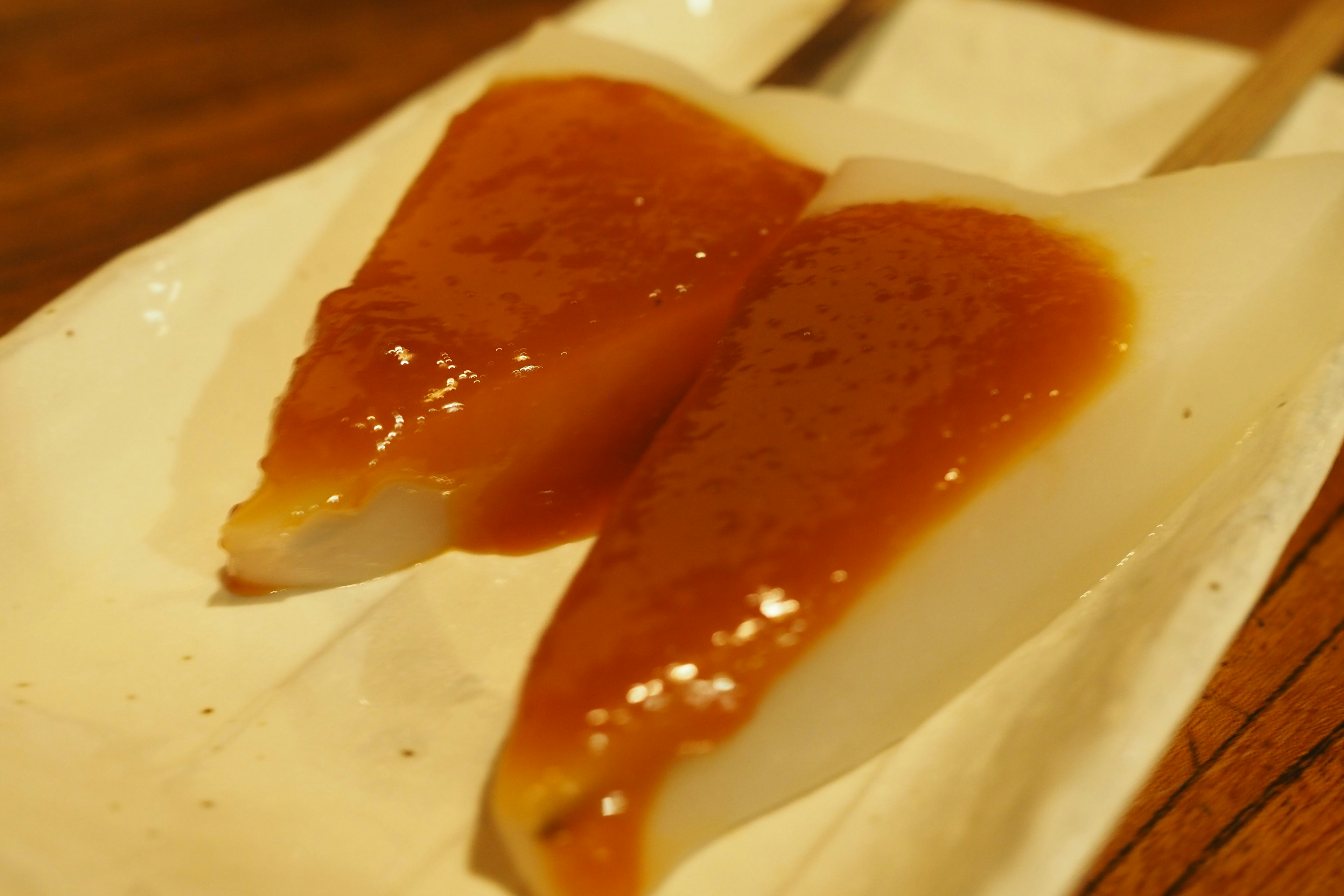 Two triangular dessert pieces with a sweet sauce on a white plate