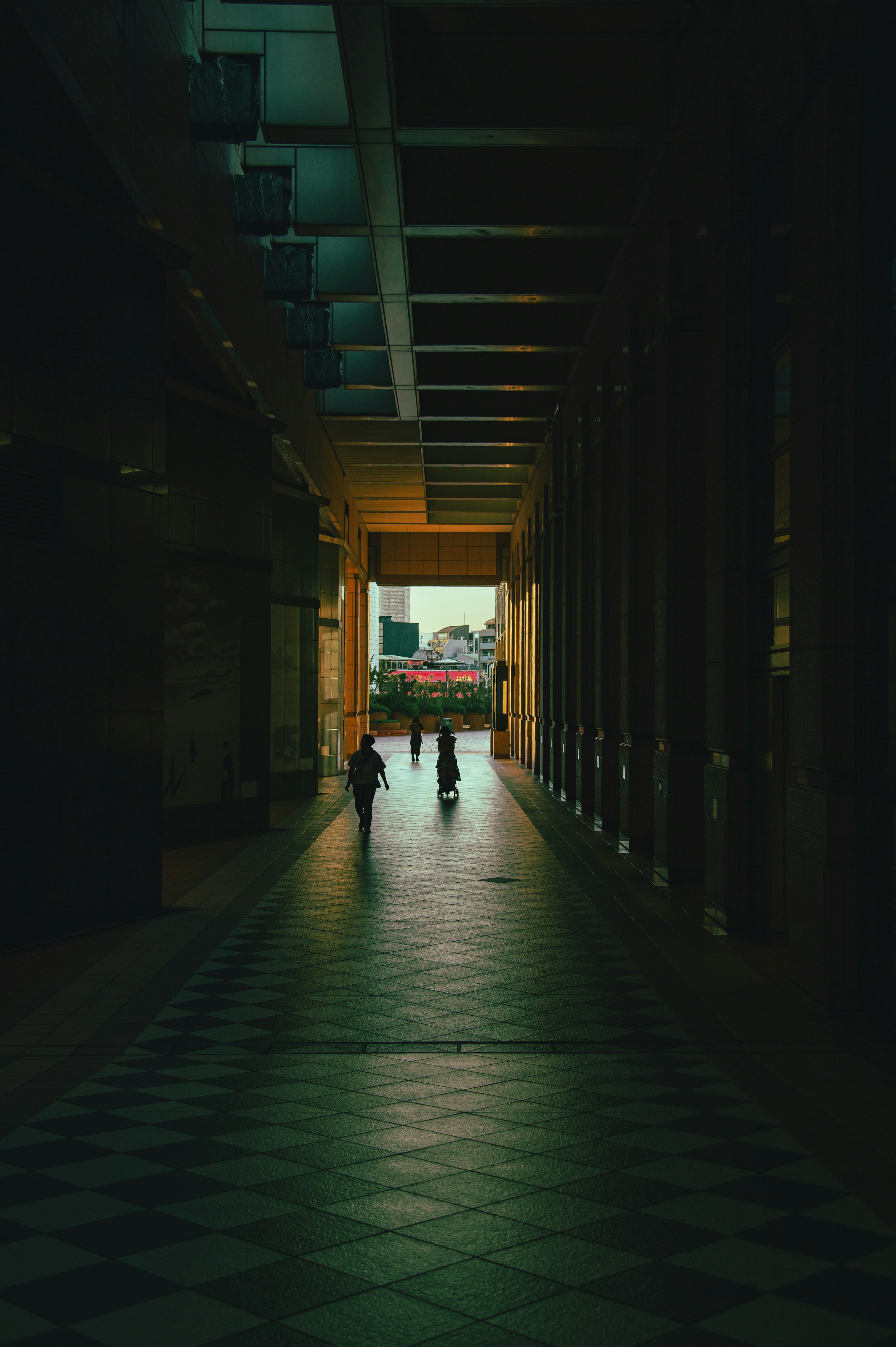 Silhouettes of people in a dark corridor with a bright exit in the distance