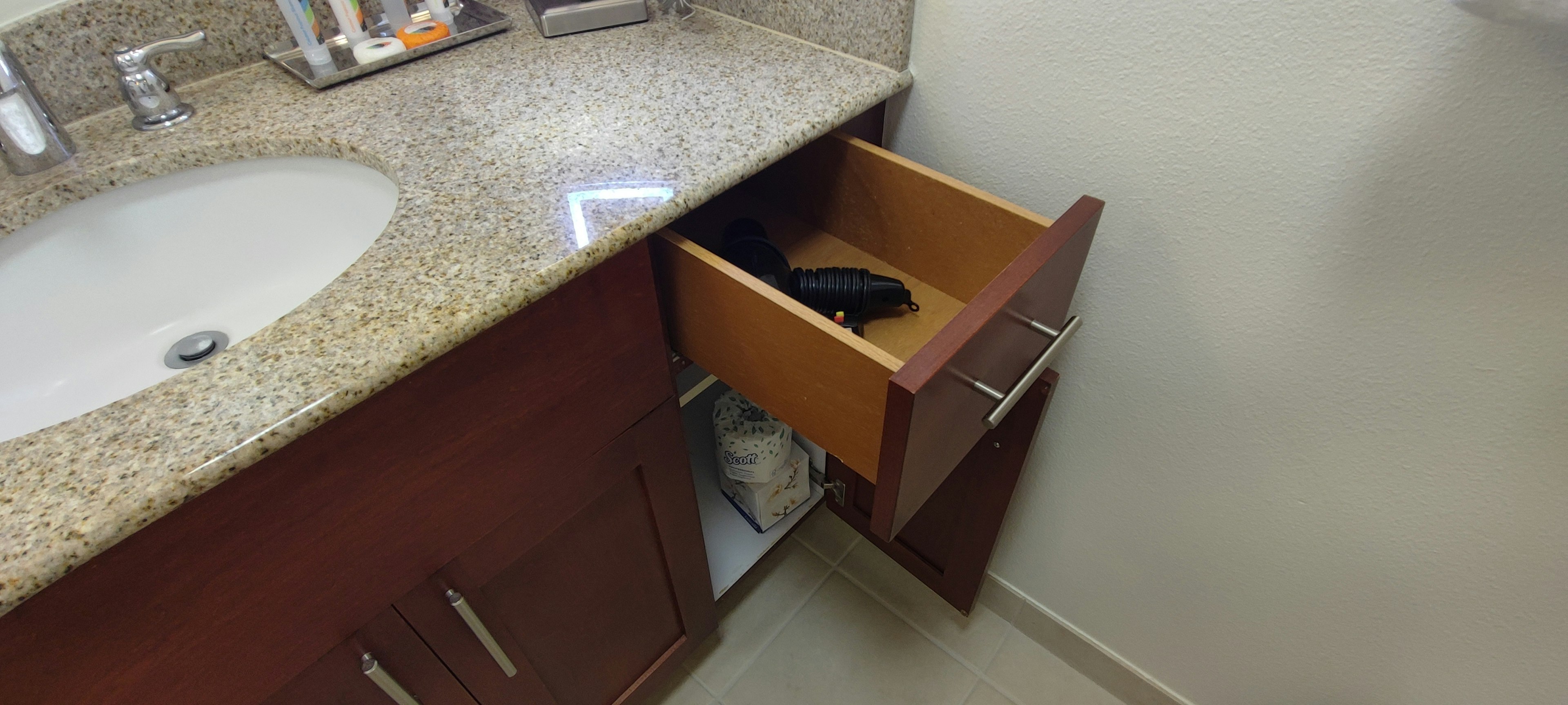 Image of a bathroom vanity with an open drawer containing a black shoe