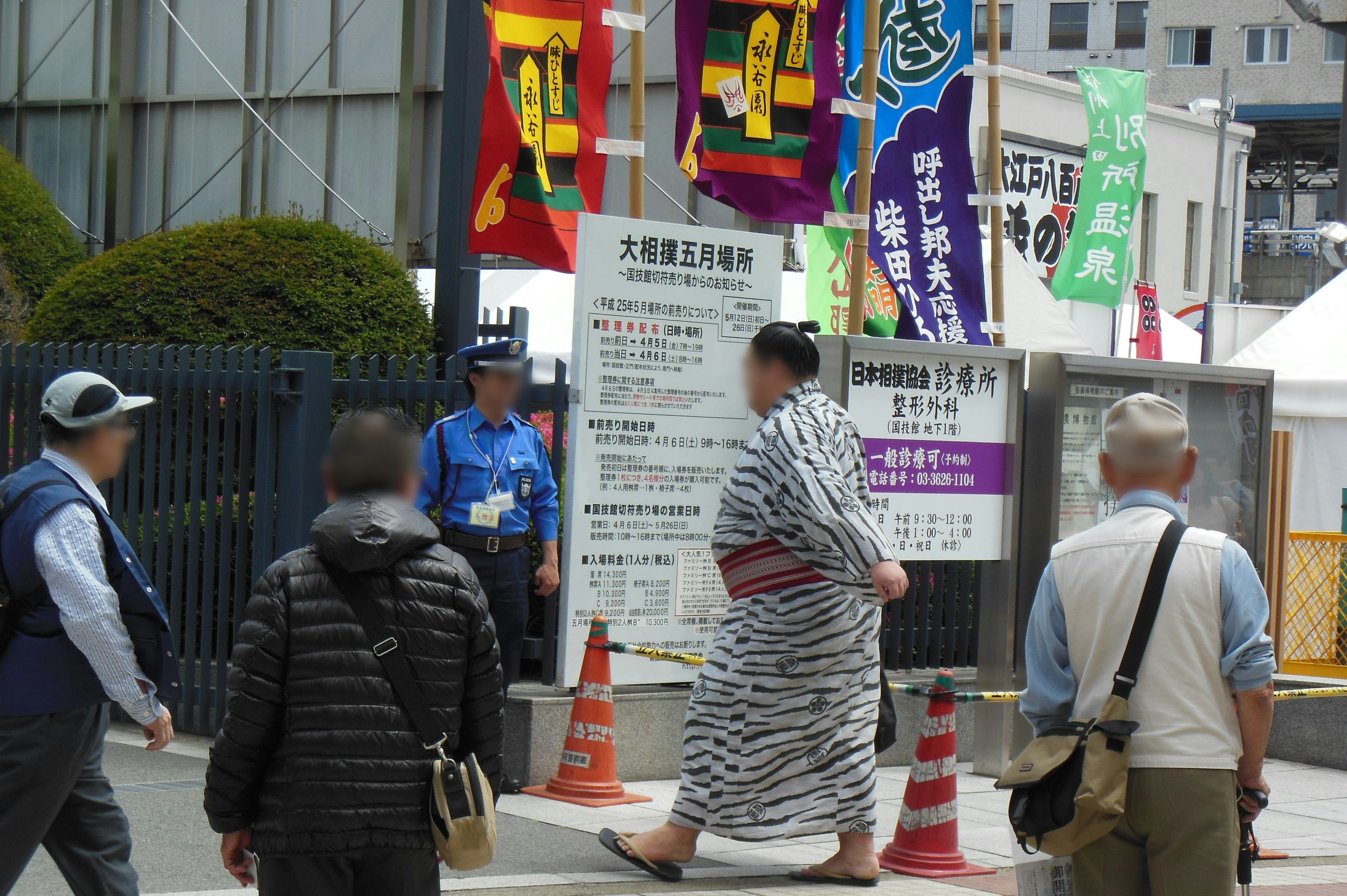 Una folla di persone che cammina con una persona in kimono tradizionale e bandiere colorate sullo sfondo