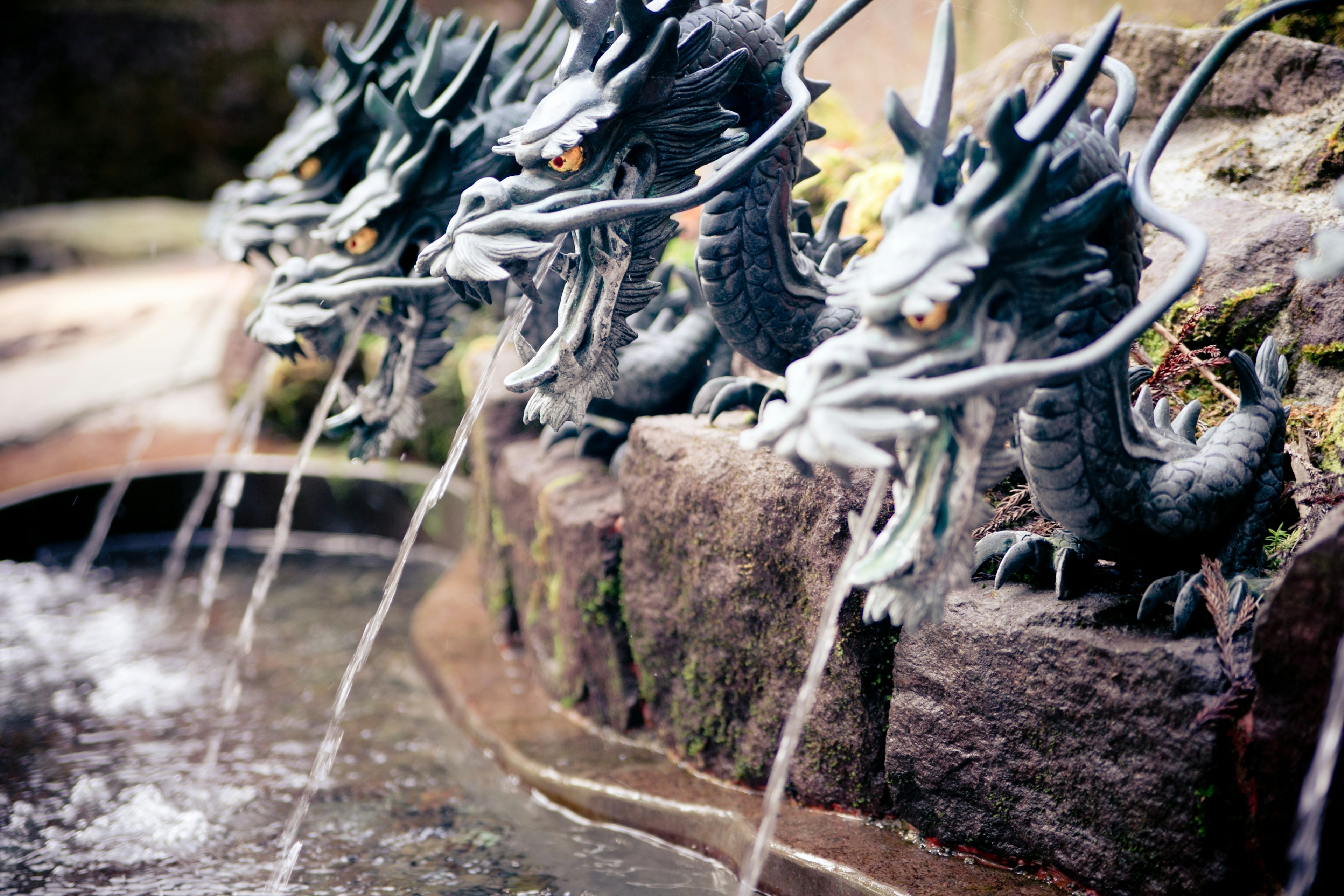 Une scène avec quatre sculptures de dragons crachant de l'eau dans un étang