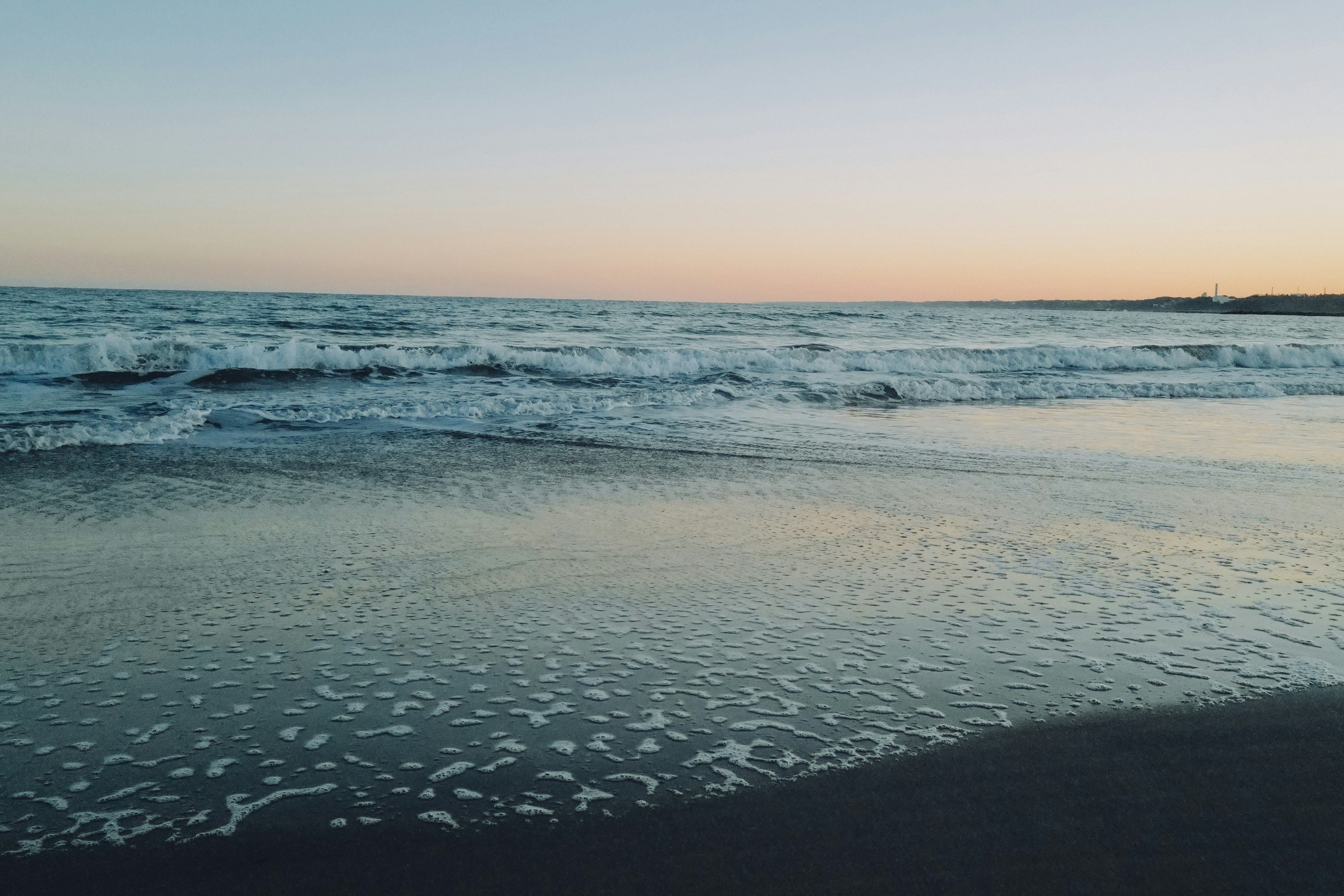 Calm sea with gentle waves and a sunset sky over the beach