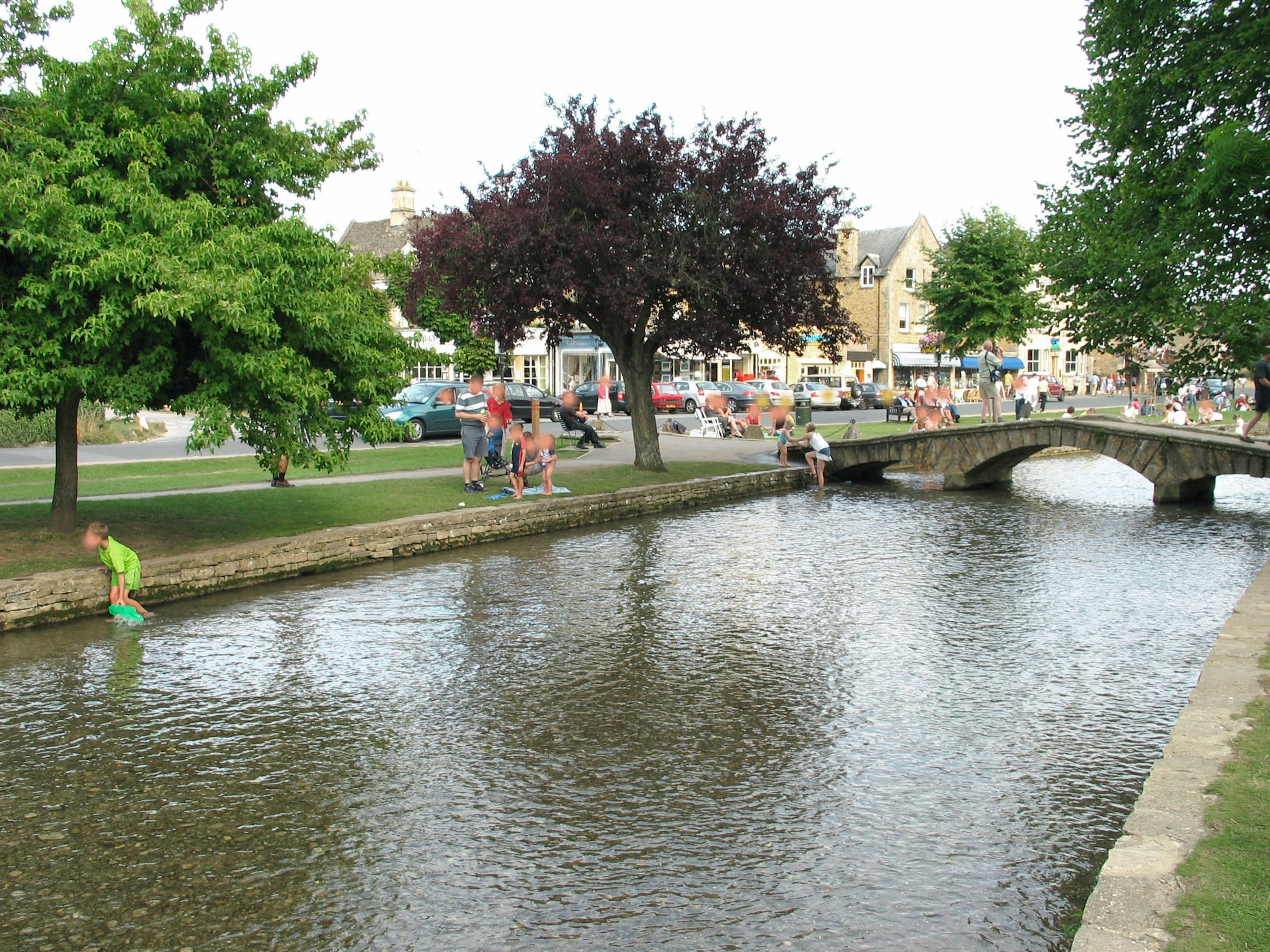 Scenic view of a river with people enjoying the outdoors and a stone bridge