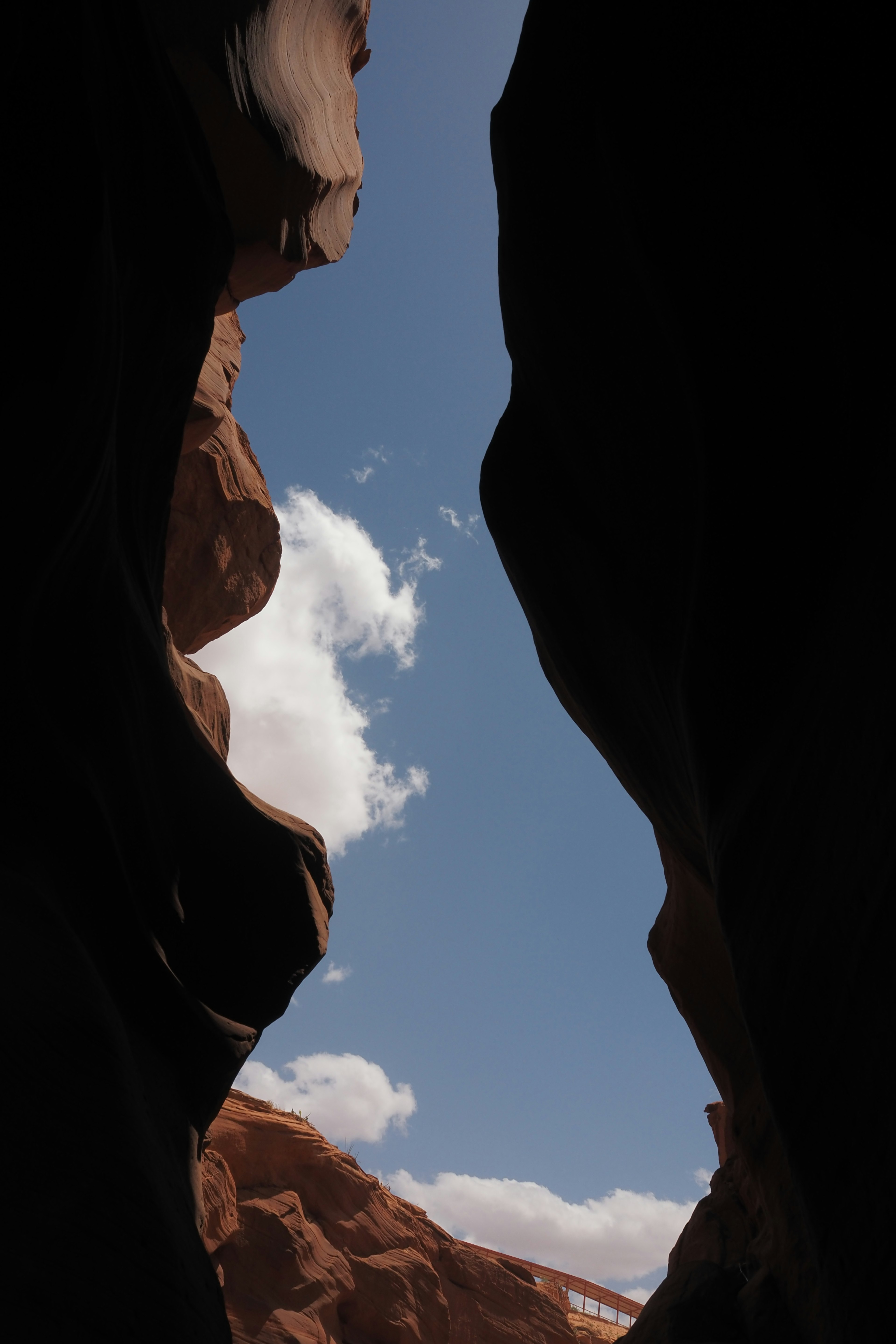 View of blue sky and white clouds through a narrow canyon