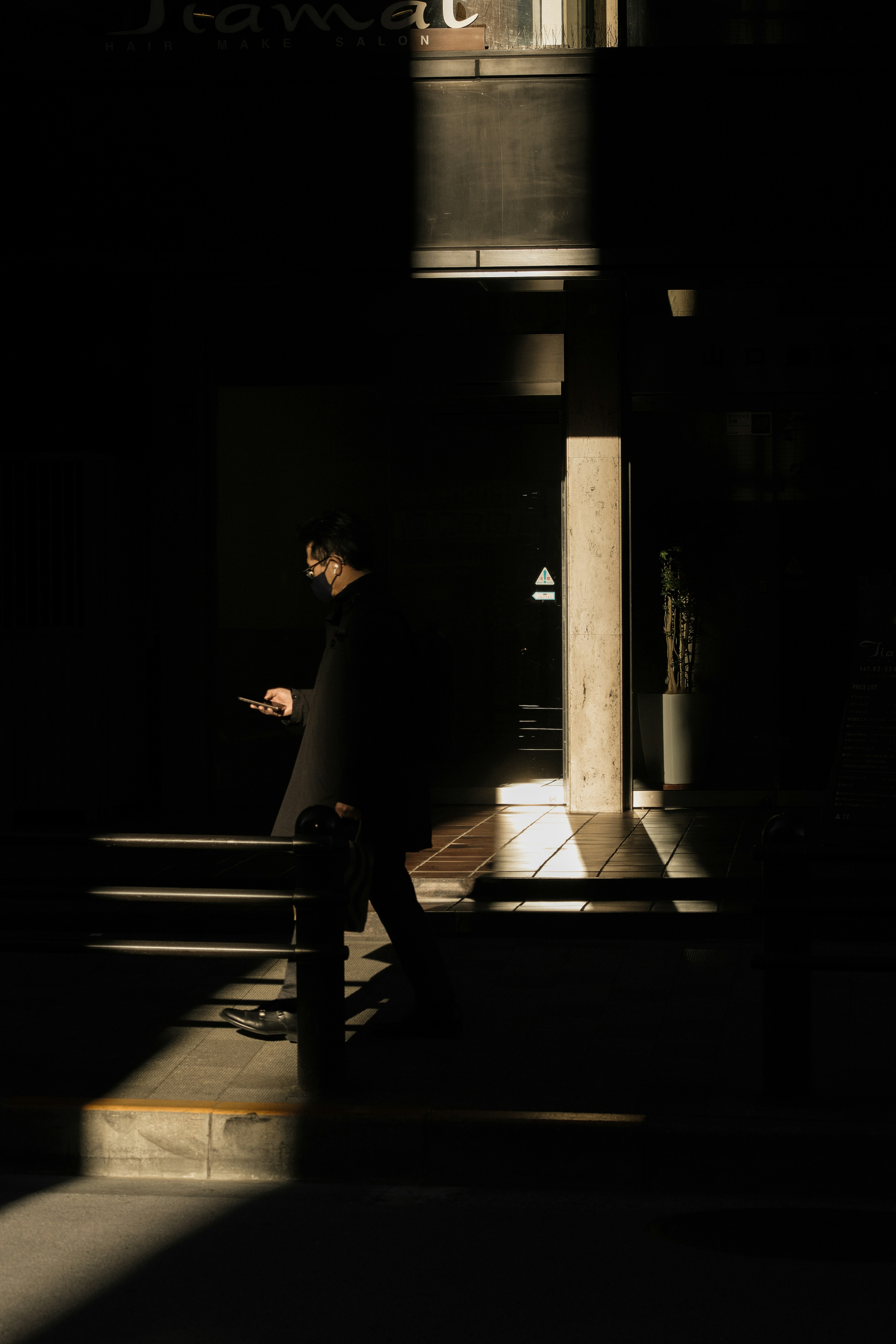 A man in dark clothing using a smartphone in a dimly lit environment