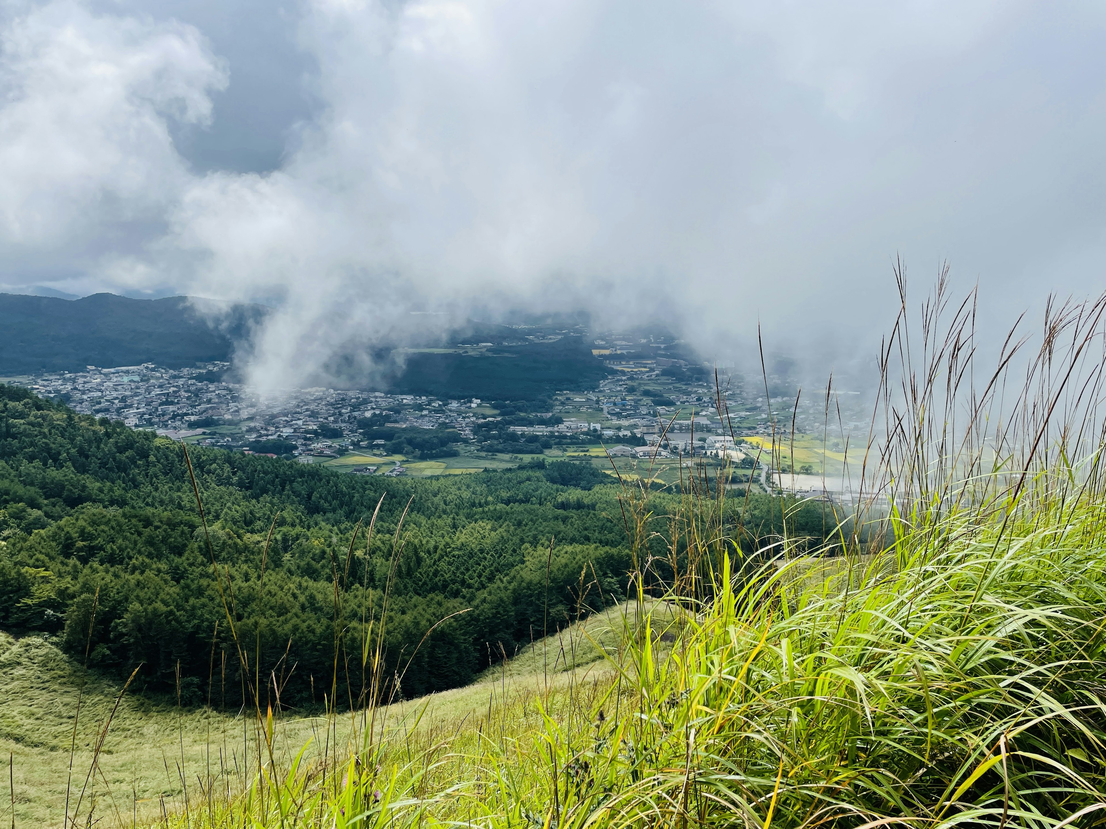 Vista escénica de montañas con nubes y praderas verdes