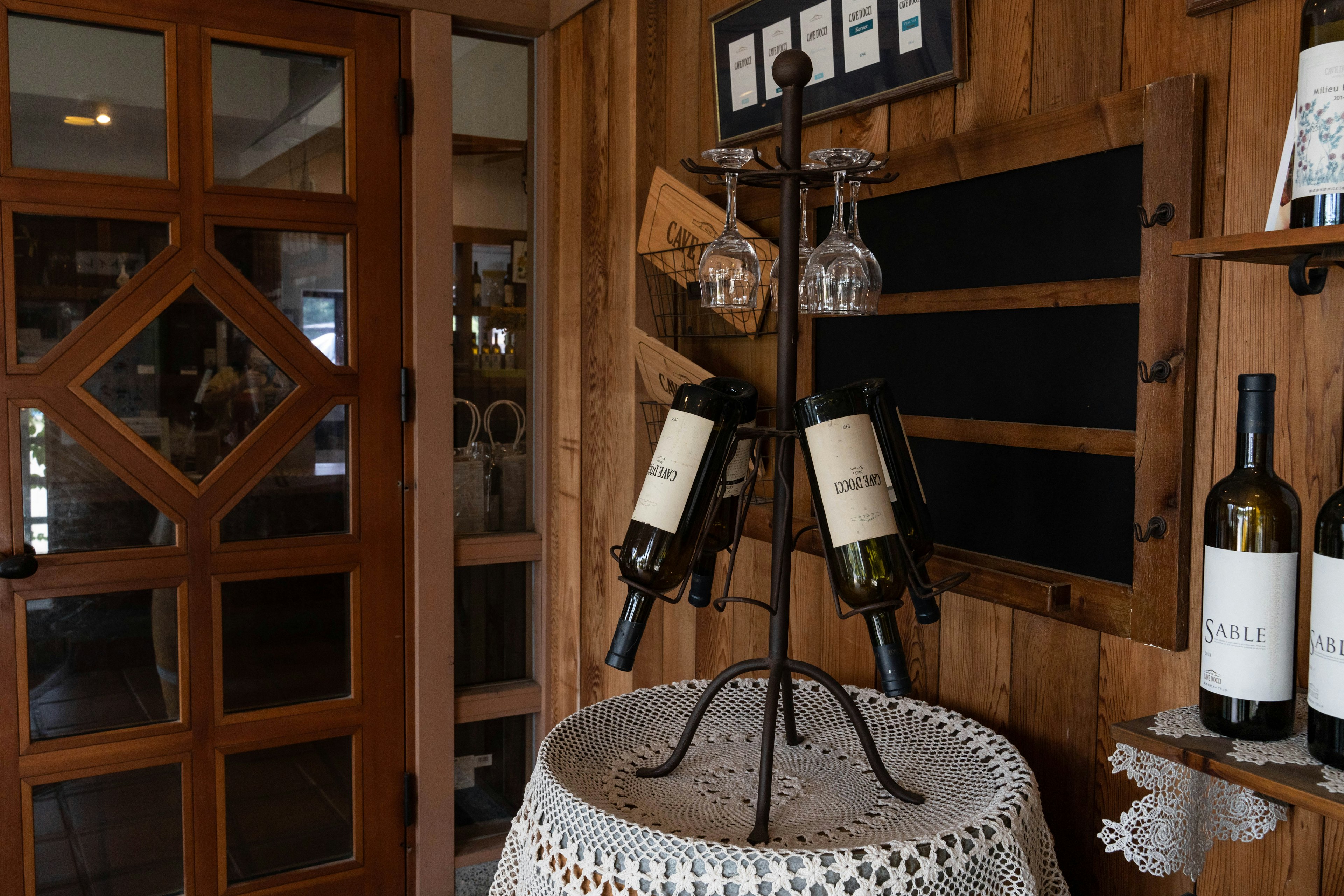 Interior con botellas de vino y copas exhibidas en una pared de madera