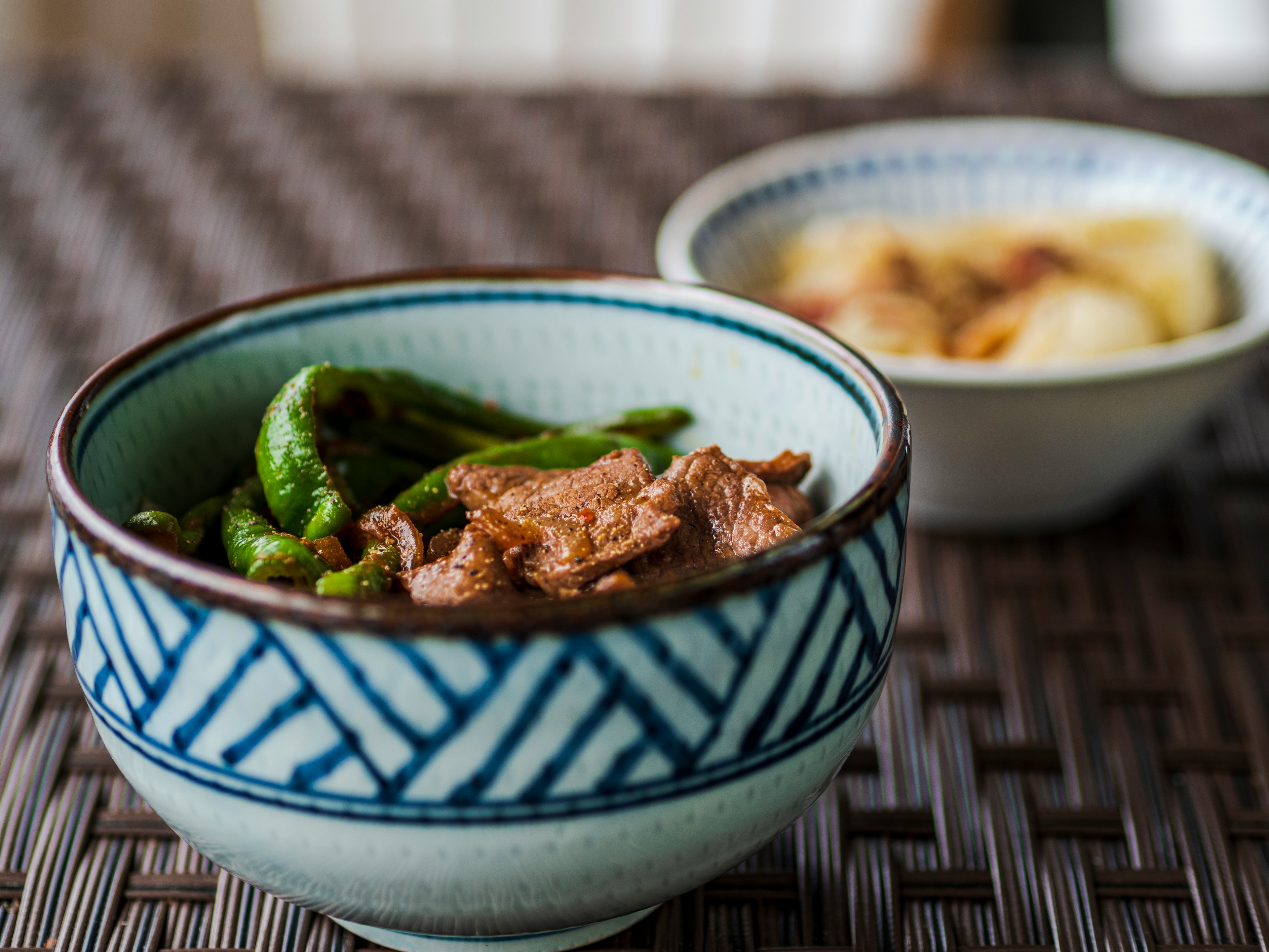 一个美丽的日本碗，装有青椒和肉的菜肴