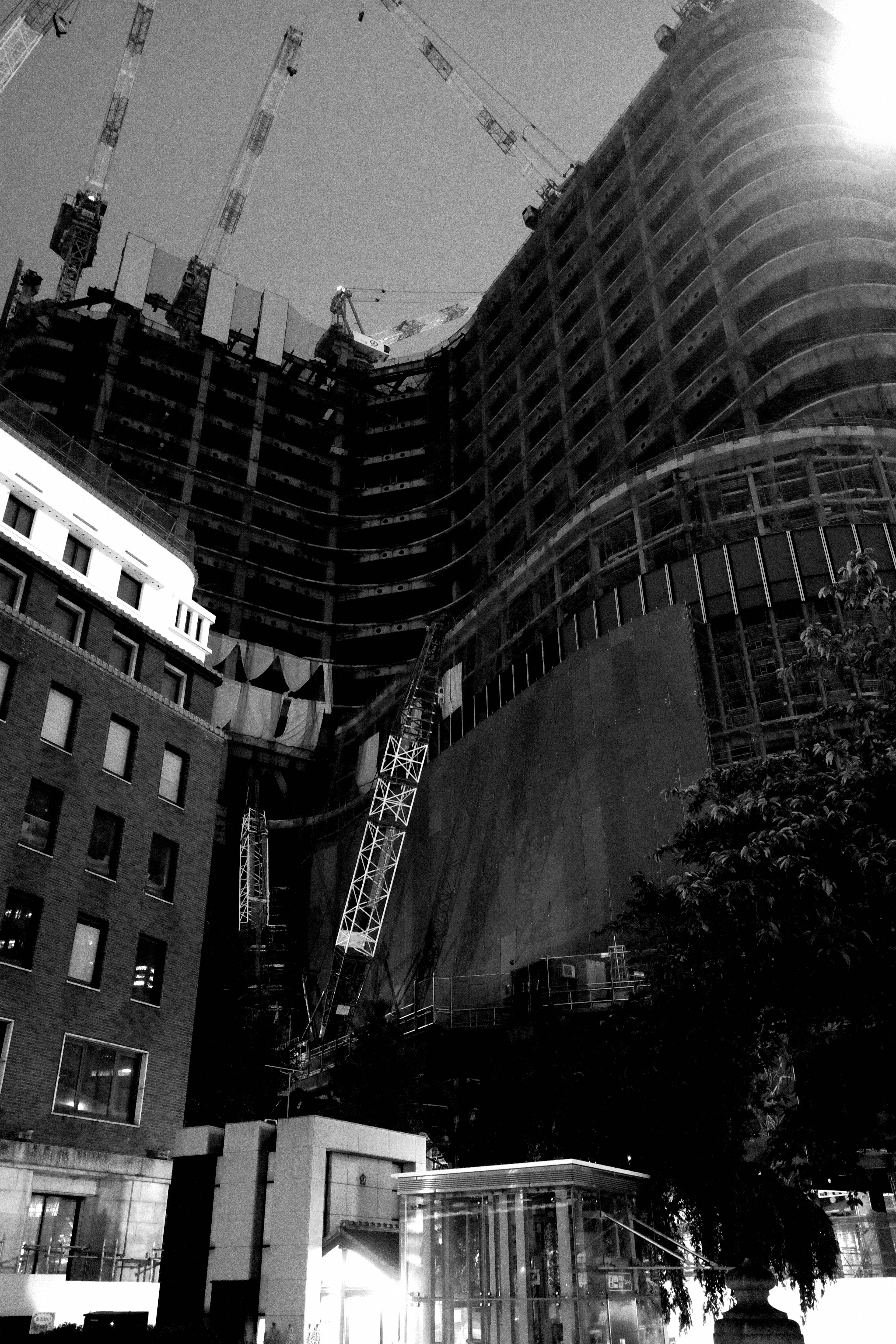 Monochrome image of a building under construction with cranes