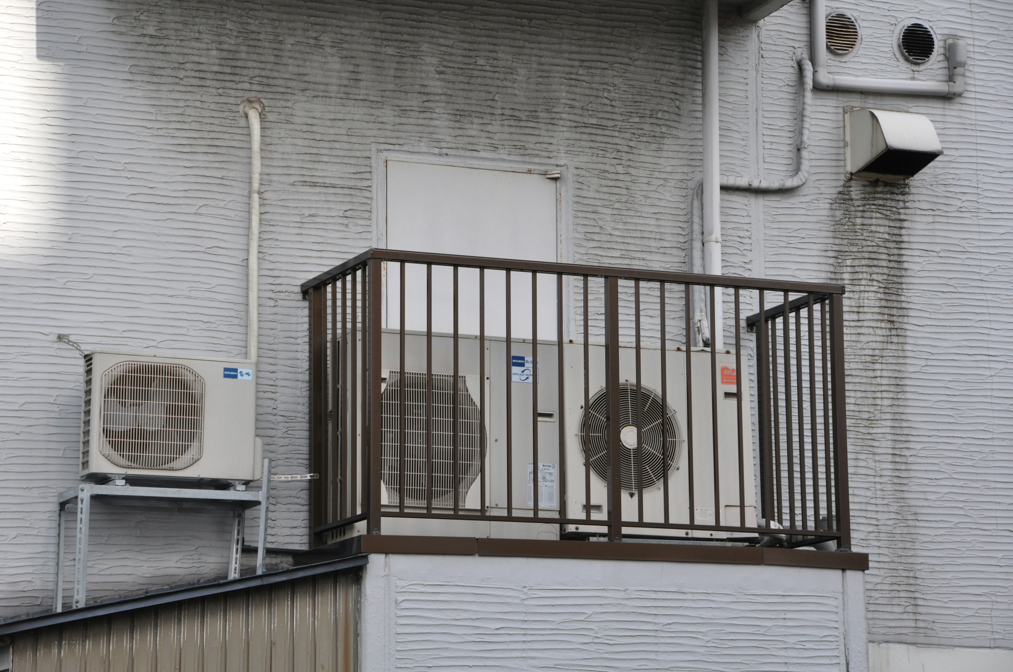 Image of air conditioning units mounted on a wall with a balcony