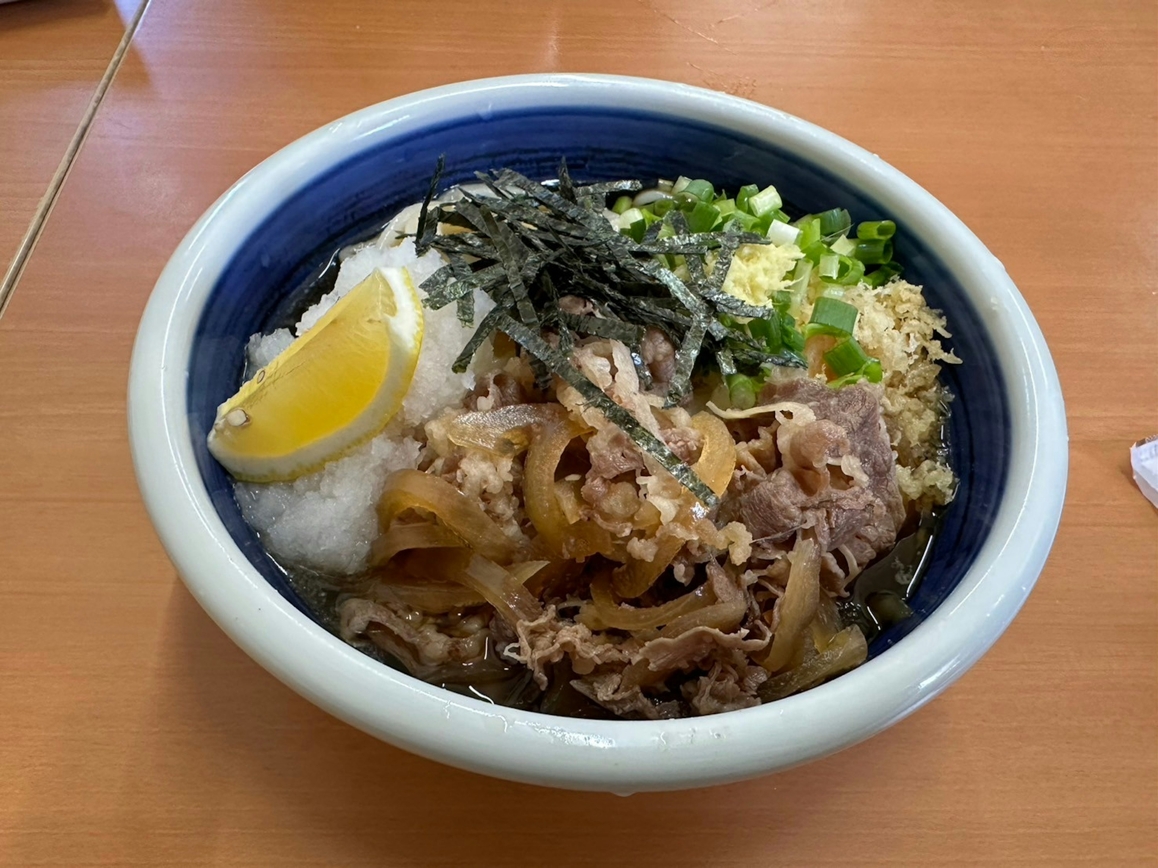 Bowl of Japanese gyudon topped with grated daikon and a slice of lemon