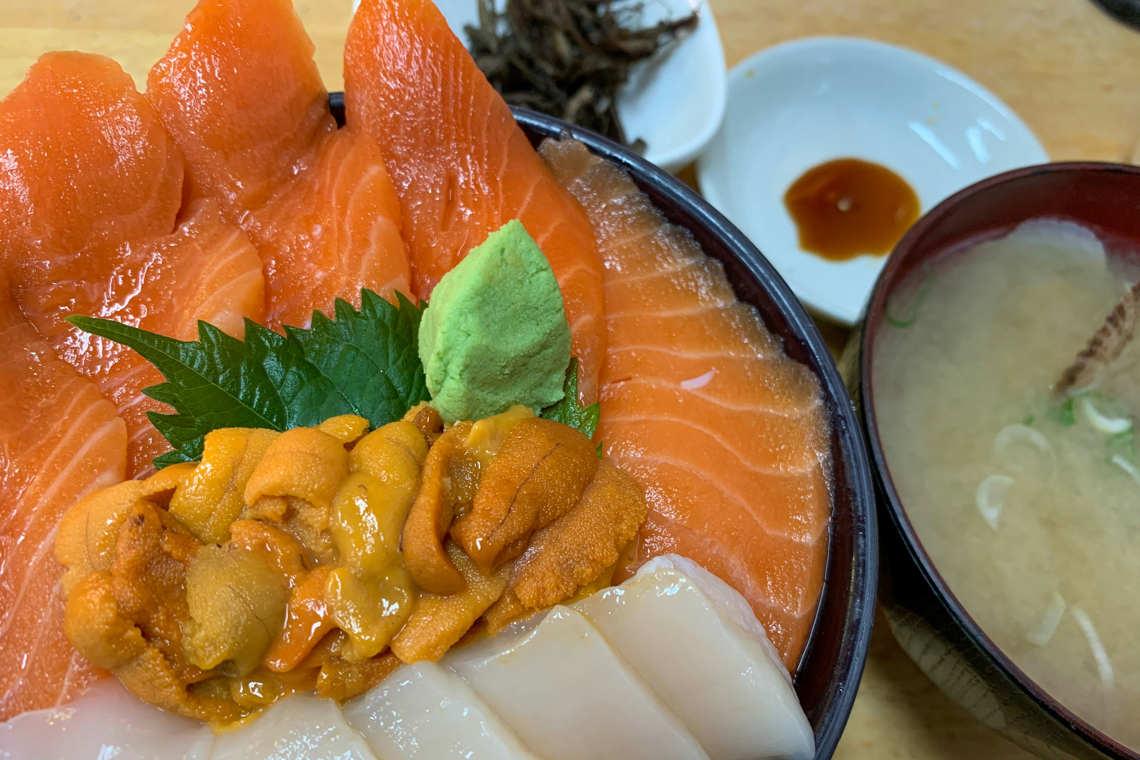 Tazón de mariscos vibrante con salmón y erizo de mar acompañado de sopa miso