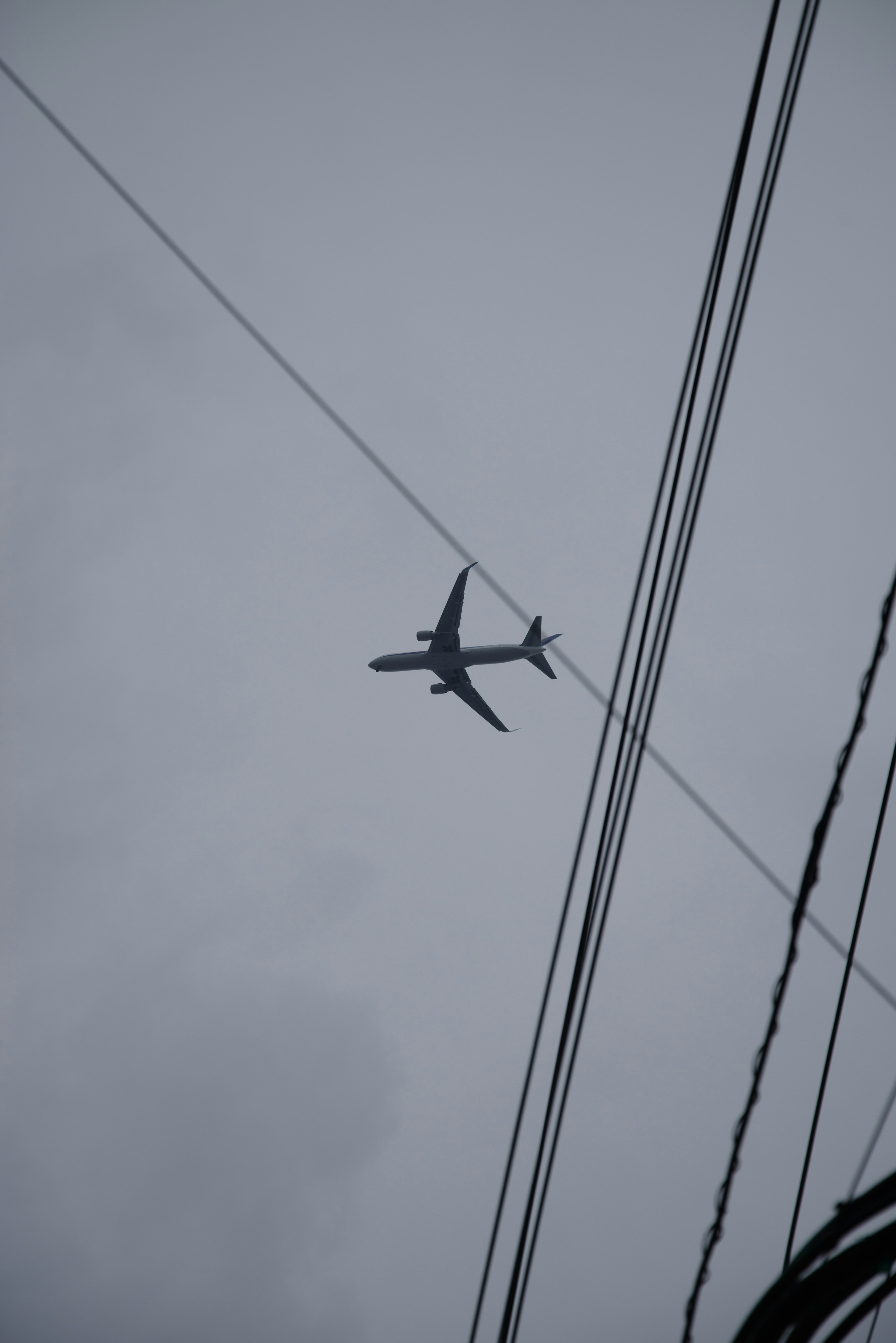 Un avión volando sobre líneas eléctricas bajo un cielo gris