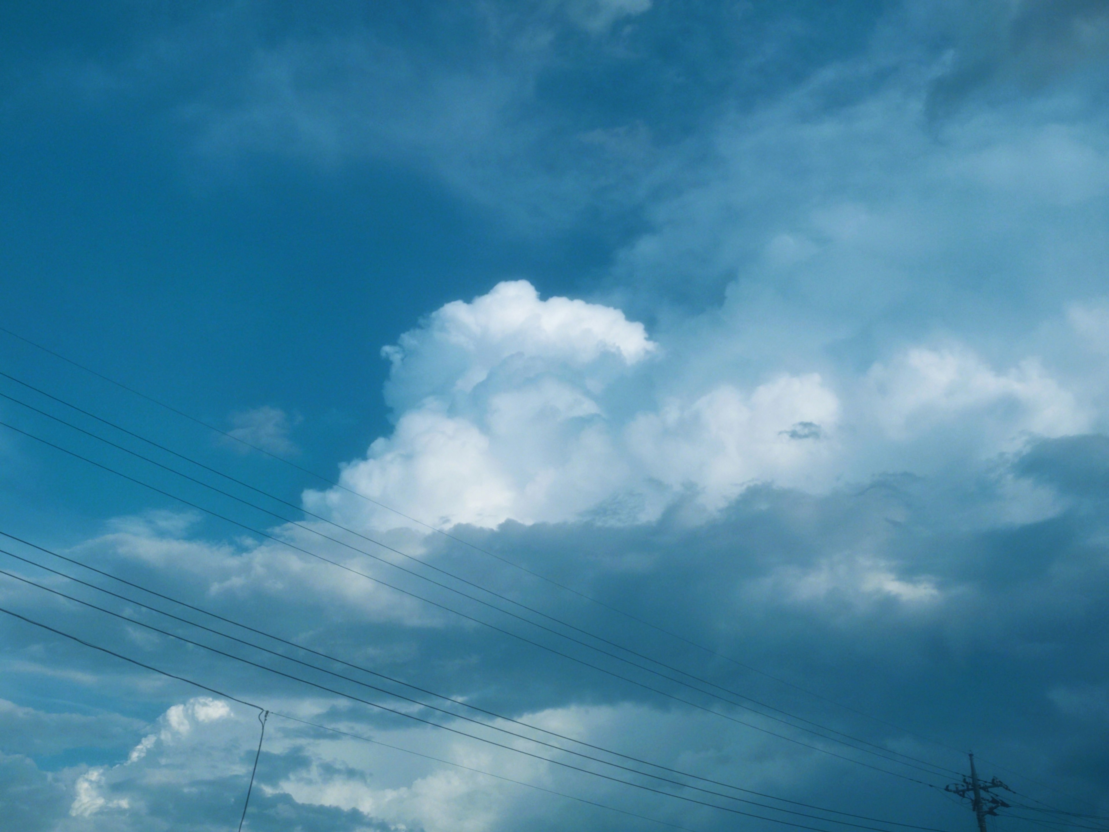 Cielo blu con nuvole e linee elettriche visibili