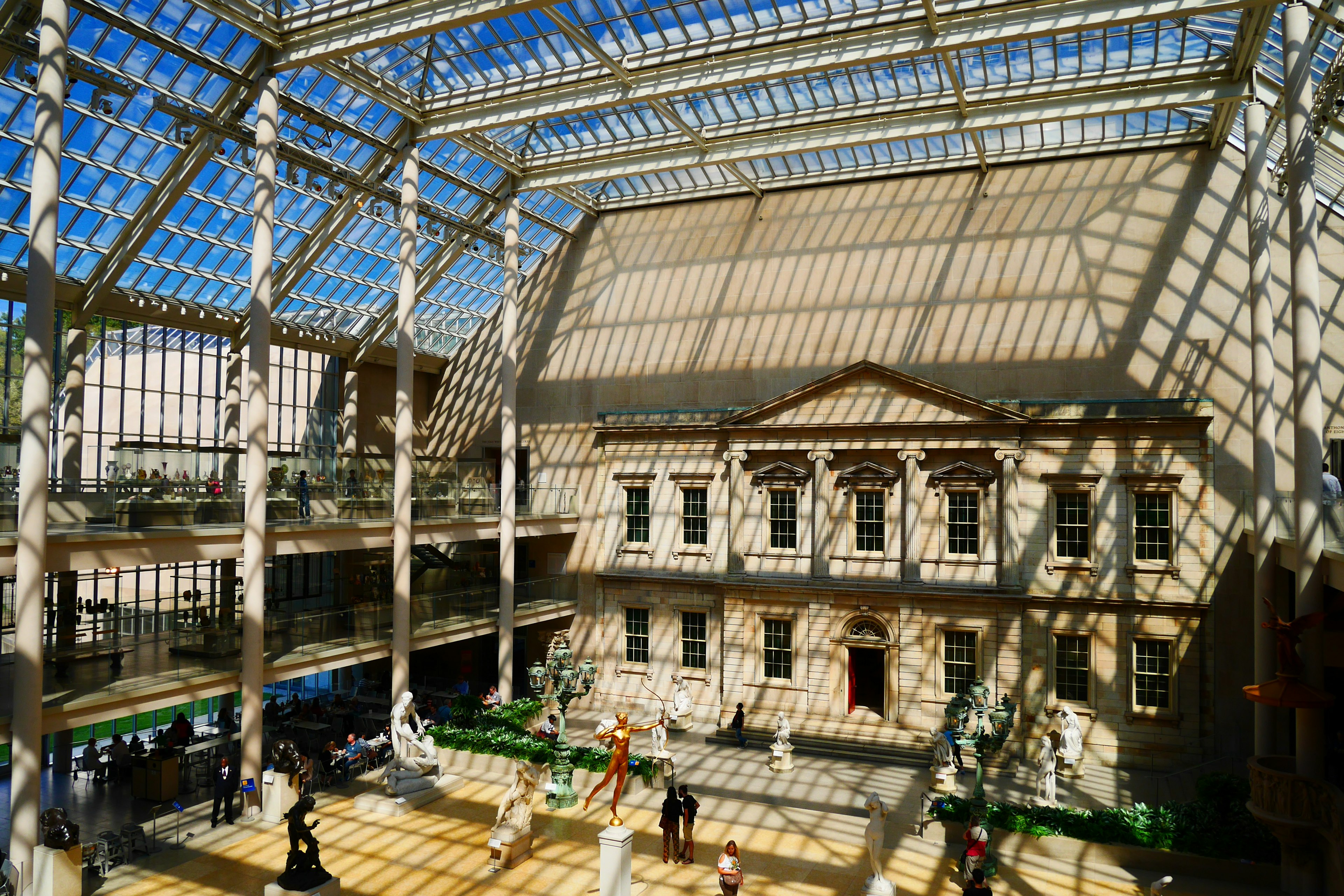 Interior de un museo con un edificio histórico bajo un techo de vidrio y sombras